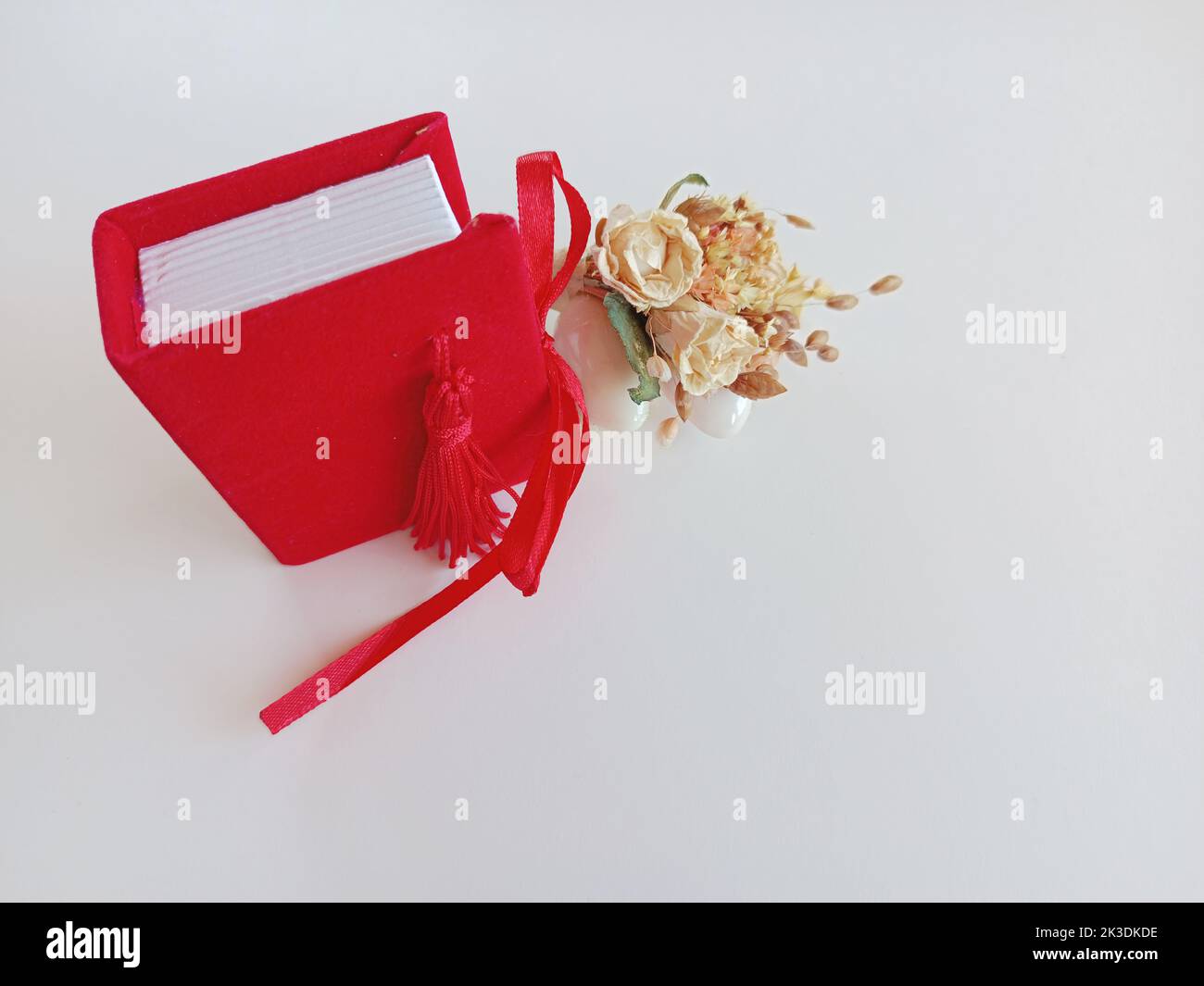 Close-up Graduation Diploma mit Red Color Gift Buch. Graduation Mortarboard. Weißer Hintergrund. Stockfoto