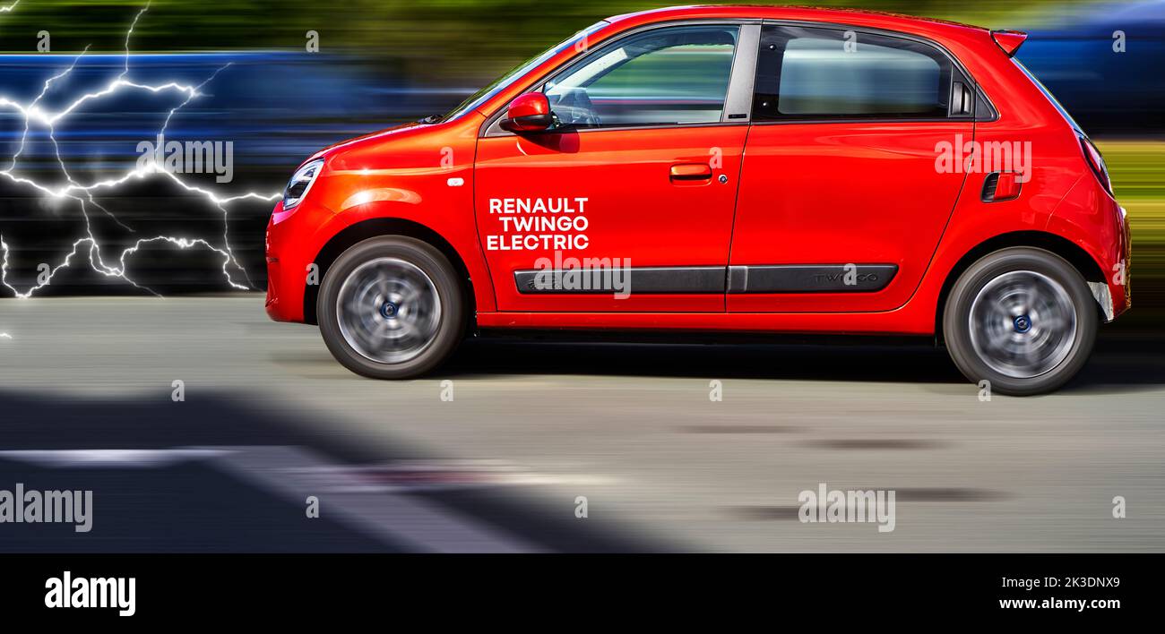 Renault Twingo elektrisch, Seitenansicht des roten Elektro-Kleinwagens vor dynamischem, unscharfem Hintergrund mit Blitzen von vorne, Fahrzeugstandort Hannover, Ge Stockfoto