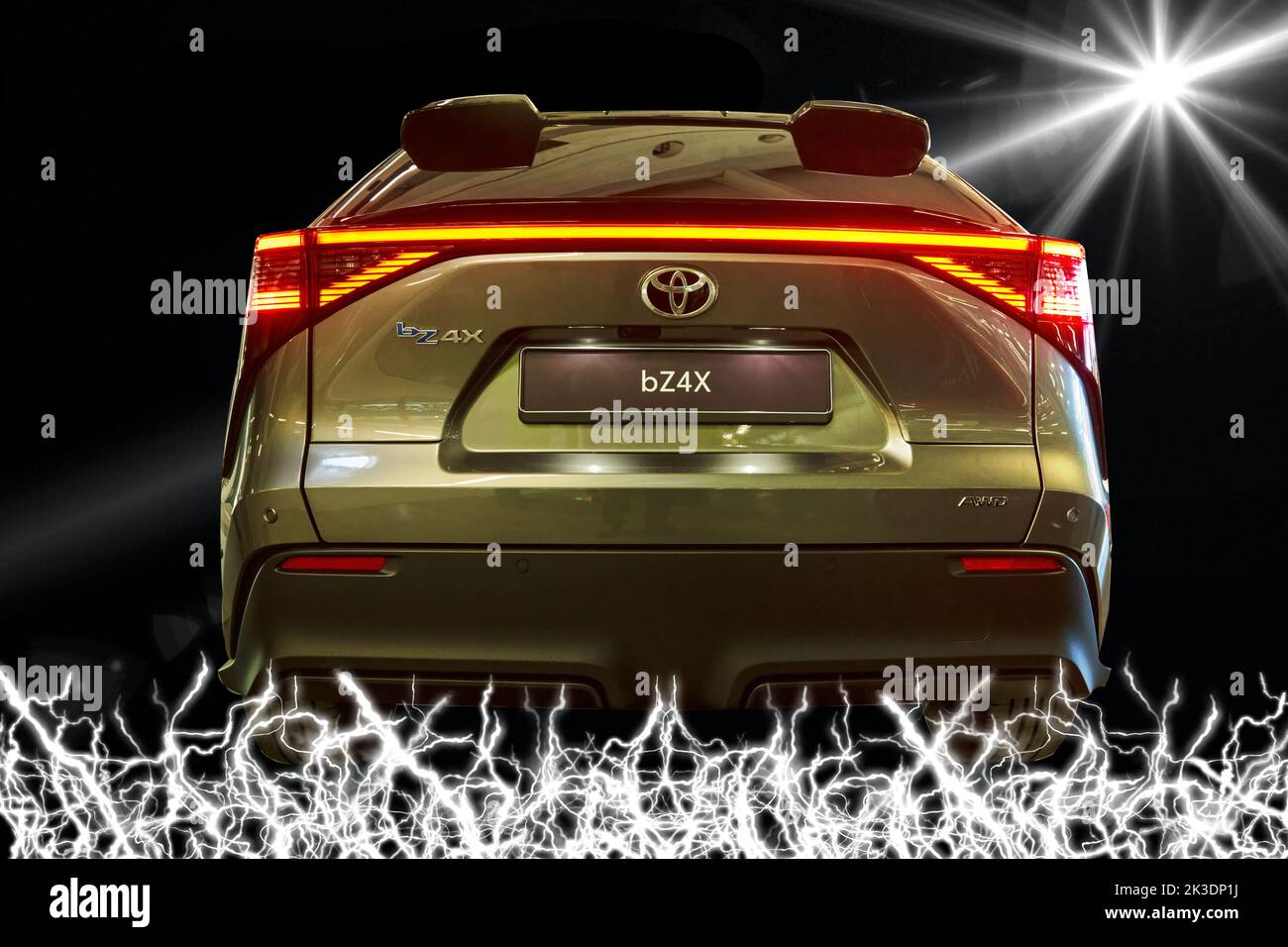 Toyota bz4X vollelektrischer SUV in der Rückansicht, Konzept mit Blitz unter dem Fahrzeug und Sonnenstrahlen für die Energieversorgung am Rand, Fahrzeugstandort Stockfoto