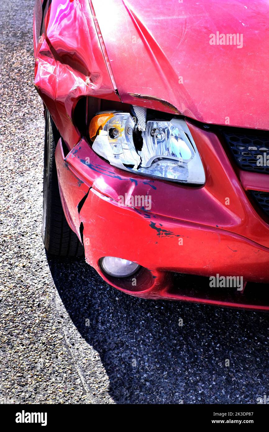 Rotes Auto mit einem beschädigten Scheinwerfer und zertrümmerten Stoßfänger nach einem Unfall Stockfoto