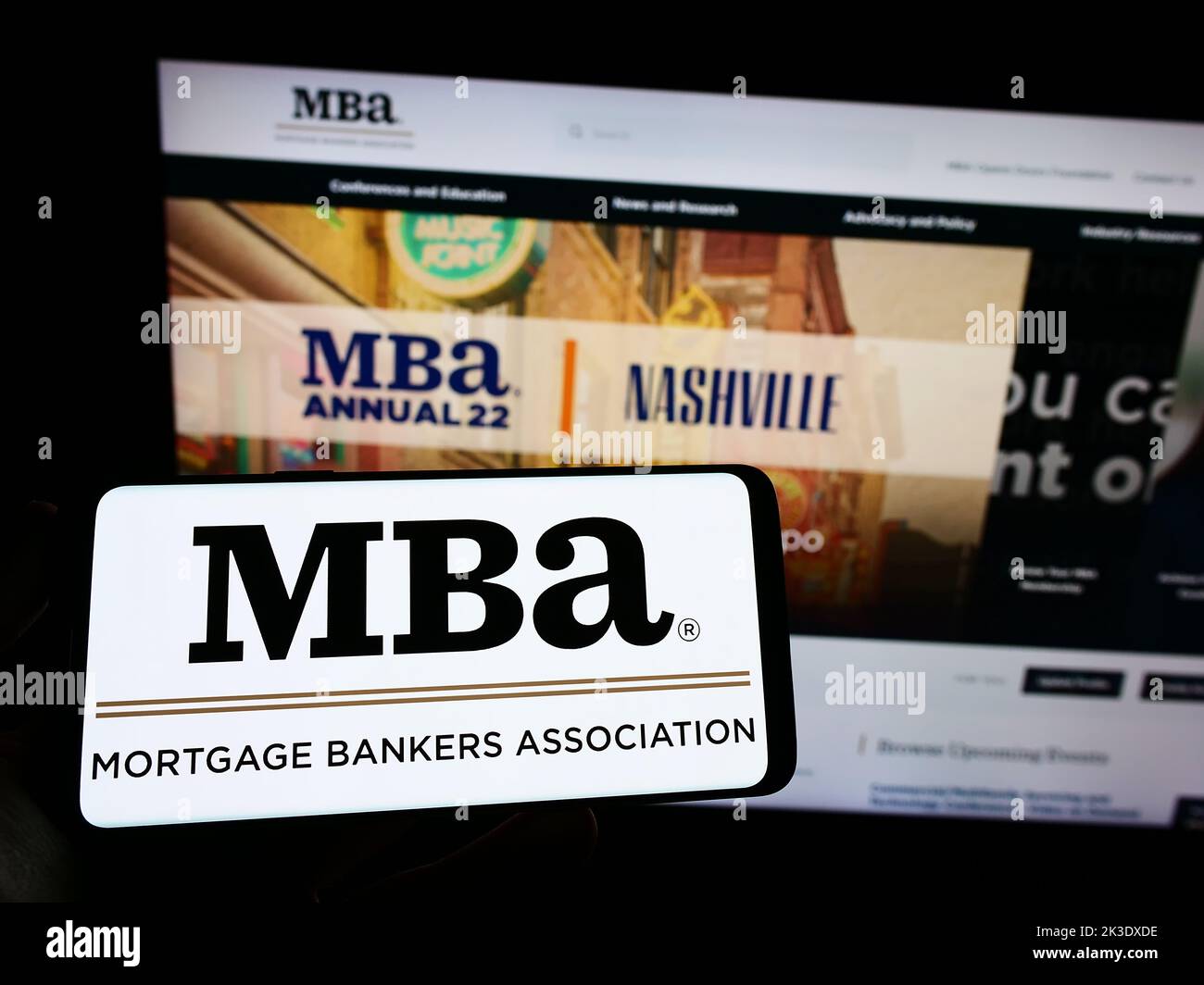 Person, die Smartphone mit Logo der Organisation Mortgage Bankers Association (MBA) auf dem Bildschirm vor der Website hält. Konzentrieren Sie sich auf die Telefonanzeige. Stockfoto