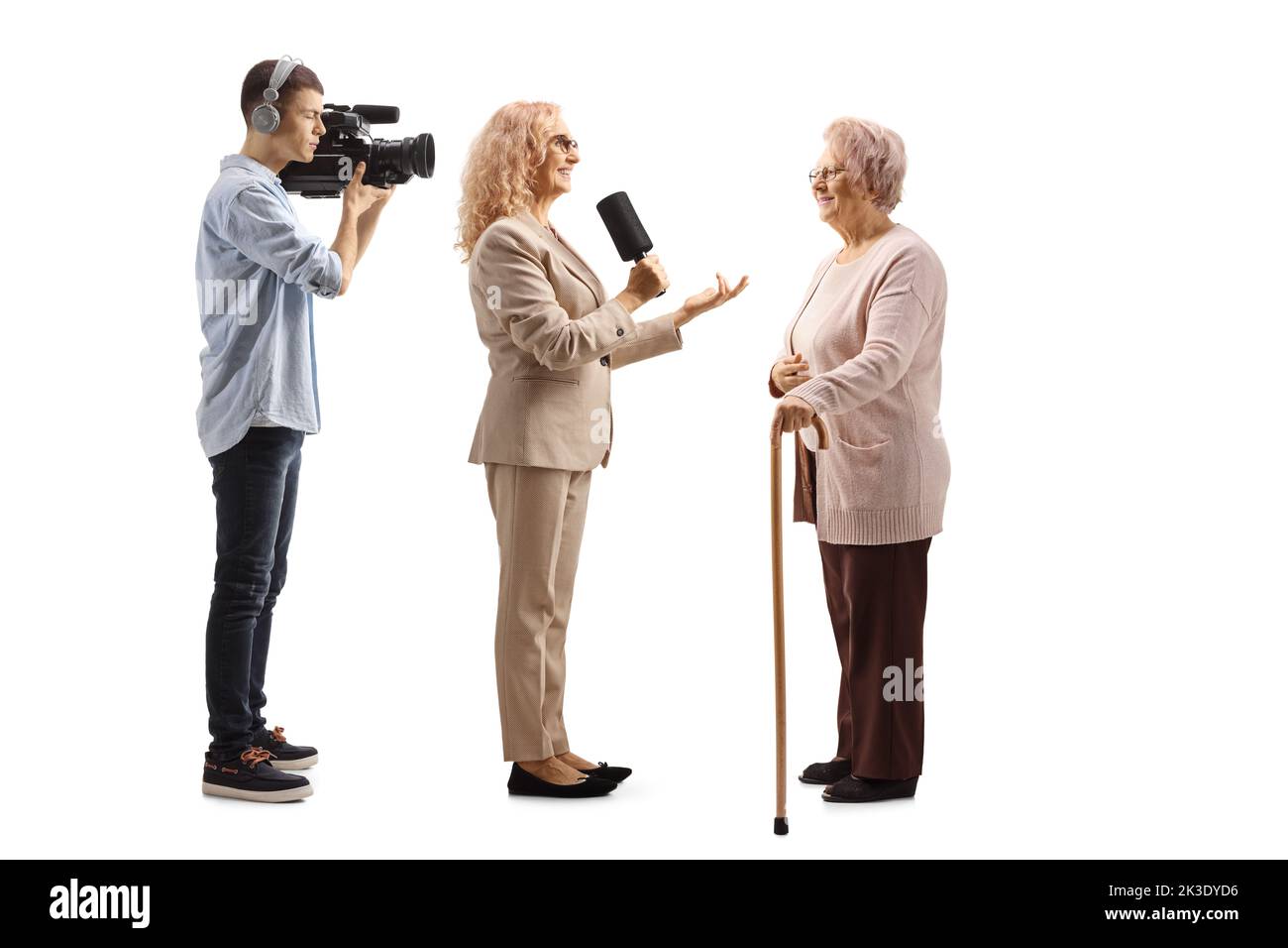 Journalistin interviewte eine ältere Frau und einen Kameramann, die isoliert auf weißem Hintergrund filmten Stockfoto