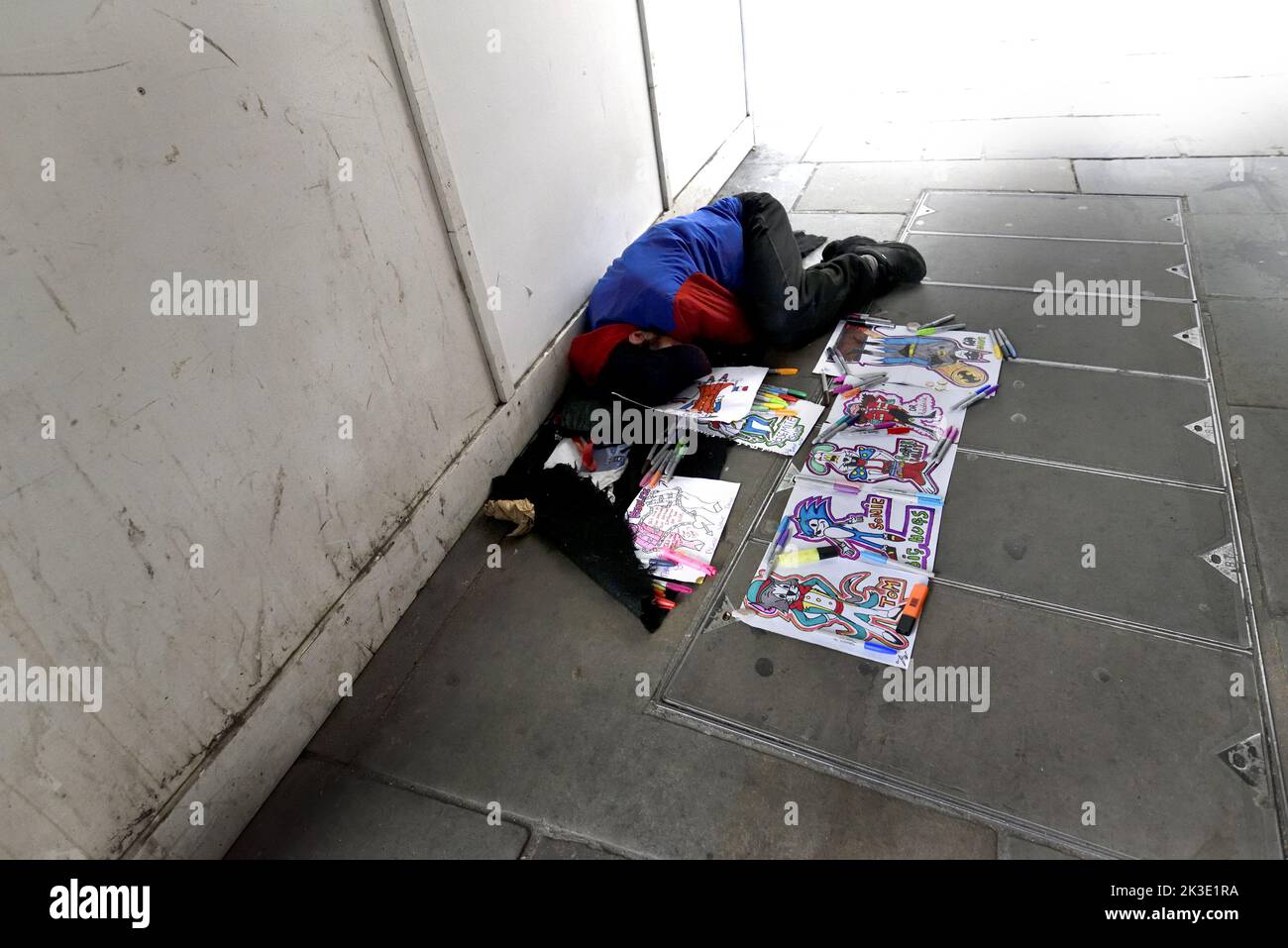 London, England, Großbritannien. Schlafender Obdachloser mit Bildern von Comic-Figuren zum Verkauf, The Strand Stockfoto
