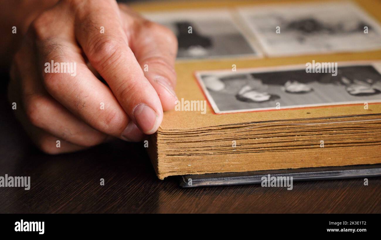 Nahaufnahme der Hände eines älteren Mannes, der alte Familienfotos in seinem Haus ansieht. Stockfoto