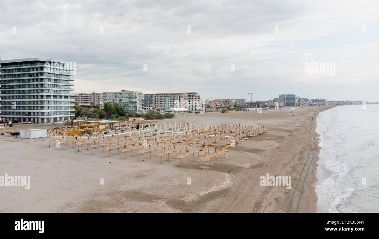 Abendstrand in Rumänien. Drohnenansicht des Mamaia Strandes in Rumänien. Sonnenschirme, Wellen am Schwarzen Meer, goldener Sand vor der Kulisse von Hotels unter CO Stockfoto