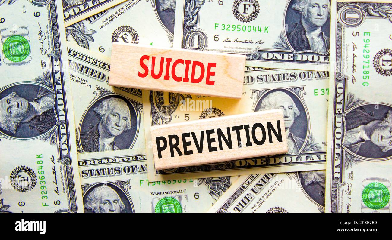 Symbol für die Suizidprävention. Konzept Wörter Selbstmordprävention auf Holzblöcken. Schöner Hintergrund von Dollarscheinen. Psychologische und Selbstmord preven Stockfoto
