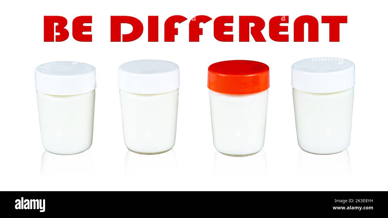 Joghurtglas mit rotem Deckel zwischen Gläsern mit weißen Deckeln. Inspirierende motivierende Zitat anders sein. Stockfoto