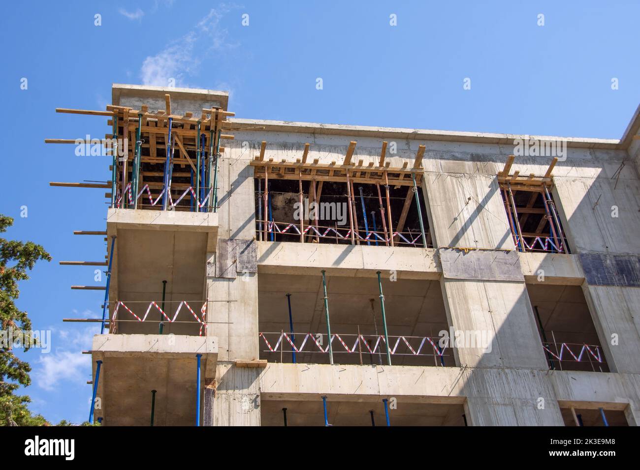 Monolithisches Haus im Bau. Elemente aus Holzschalung zum Betongießen auf einer Baustelle. Montage des Teleskopständers für die Installation Stockfoto