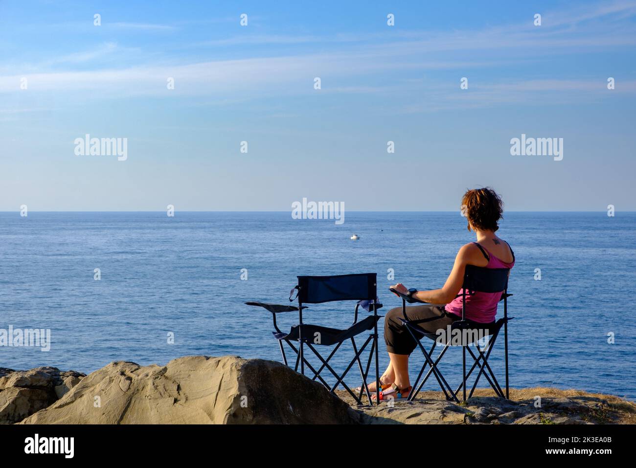 Frau, die sich vor dem Atlantischen Ozean in der Nähe von Zumaia, Baskenland, Spanien, entspannt Stockfoto