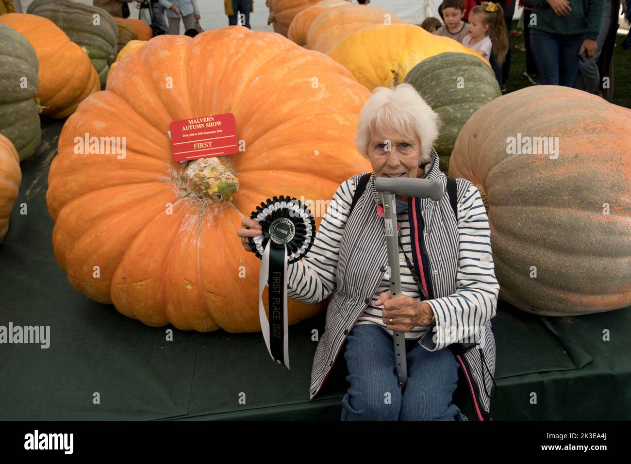 Frau, die an riesigen Kürbissen sitzt, ist ein Teil des riesigen Gemüses auf der Three Counties Autumn Show Great Malvern, Großbritannien Stockfoto