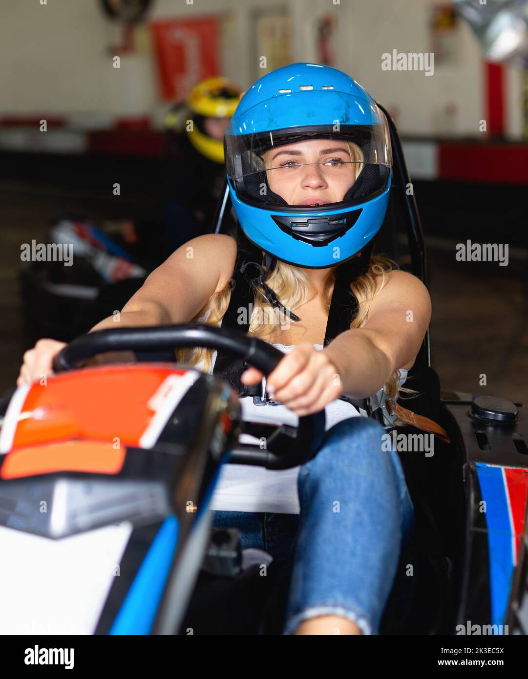 Mädchen und ihre Freunde, die auf Rennwagen auf Kart-Rennstrecke gegeneinander antreten Stockfoto