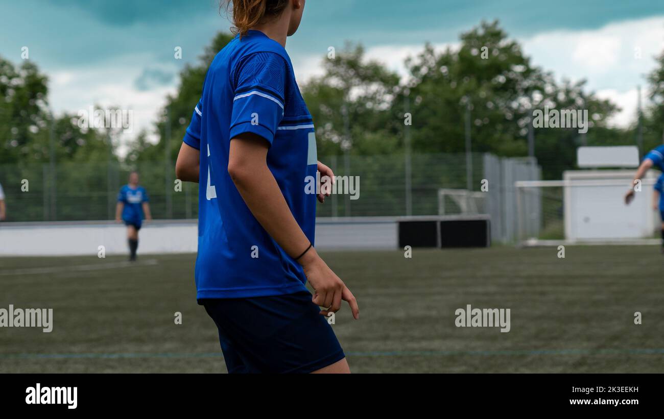 Fußballspielerin in einem Spiel mit anderen Fußballspielern im Hintergrund an einem Sommertag Stockfoto