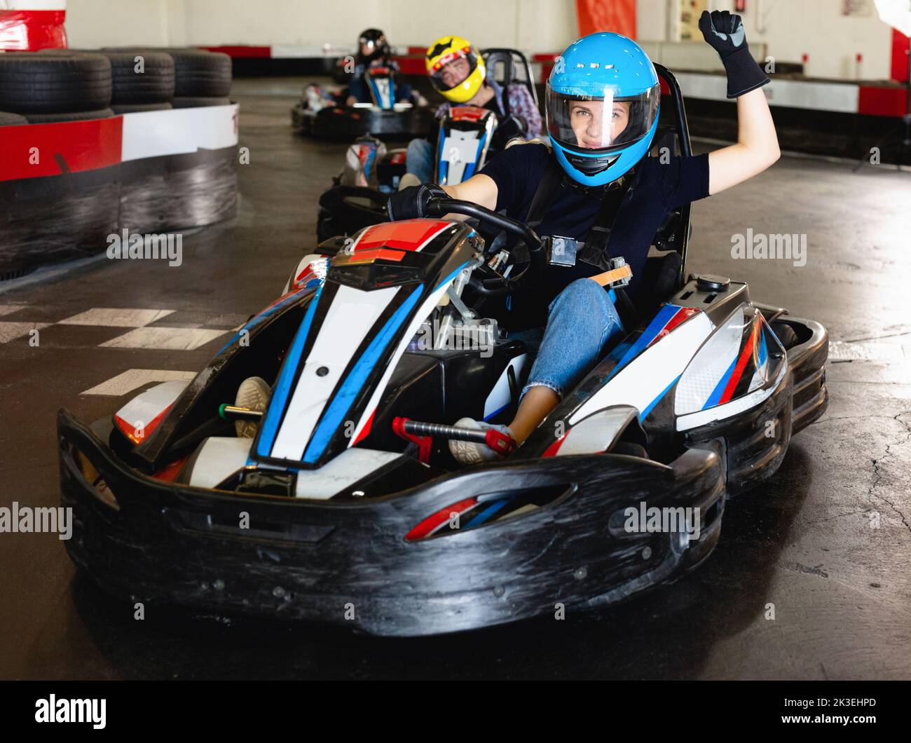 Mädchen und ihre Freunde, die auf Rennwagen auf Kart-Rennstrecke gegeneinander antreten Stockfoto