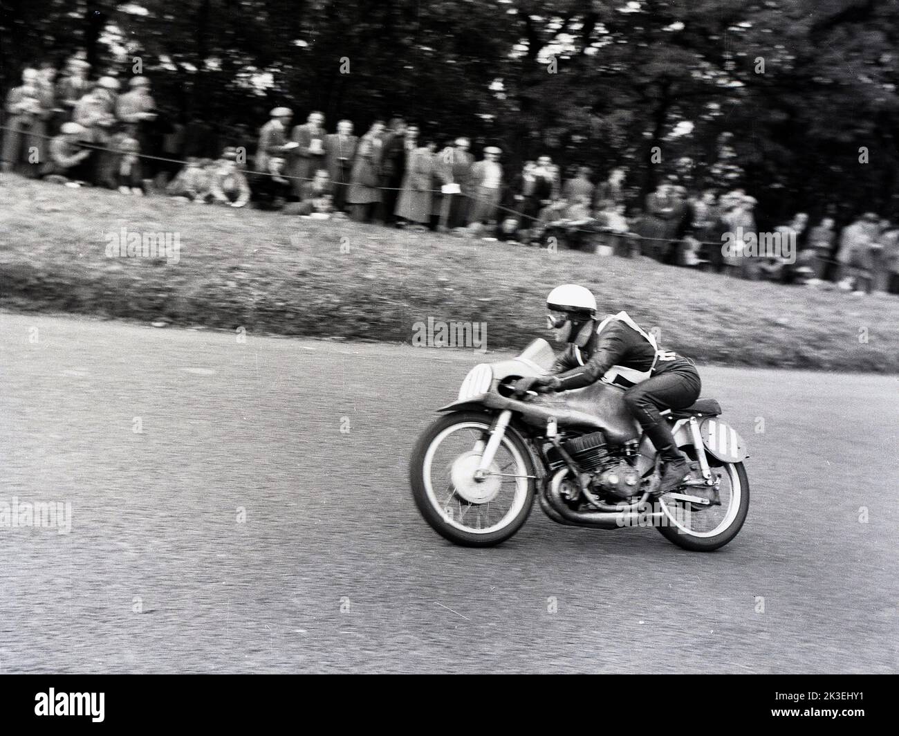 1954, historisch, Zuschauer beobachten einen Motorradfahrer auf dem Platz bei den Scarborough-Rennen, England, Großbritannien. Die berühmte Oliver’s Mount Road Rennstrecke ist Englands einzige natürliche „Road“ Rennstrecke, bekannt als „Mini TT“. Die anspruchsvolle, hügelige Strecke liegt in der Nähe von Scarboroughs Strandpromenade, daher wurden die Rennen traditionell als Scarborough-Rennen bezeichnet. Stockfoto