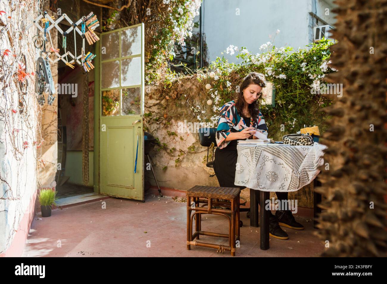 französische kaukasische Erwachsene Frau, die auf der Terrasse ihres Hauses sitzt, studiert, durch ein Notizbuch blättert und Notizen macht, Universitätsstudentin Konzept wi Stockfoto