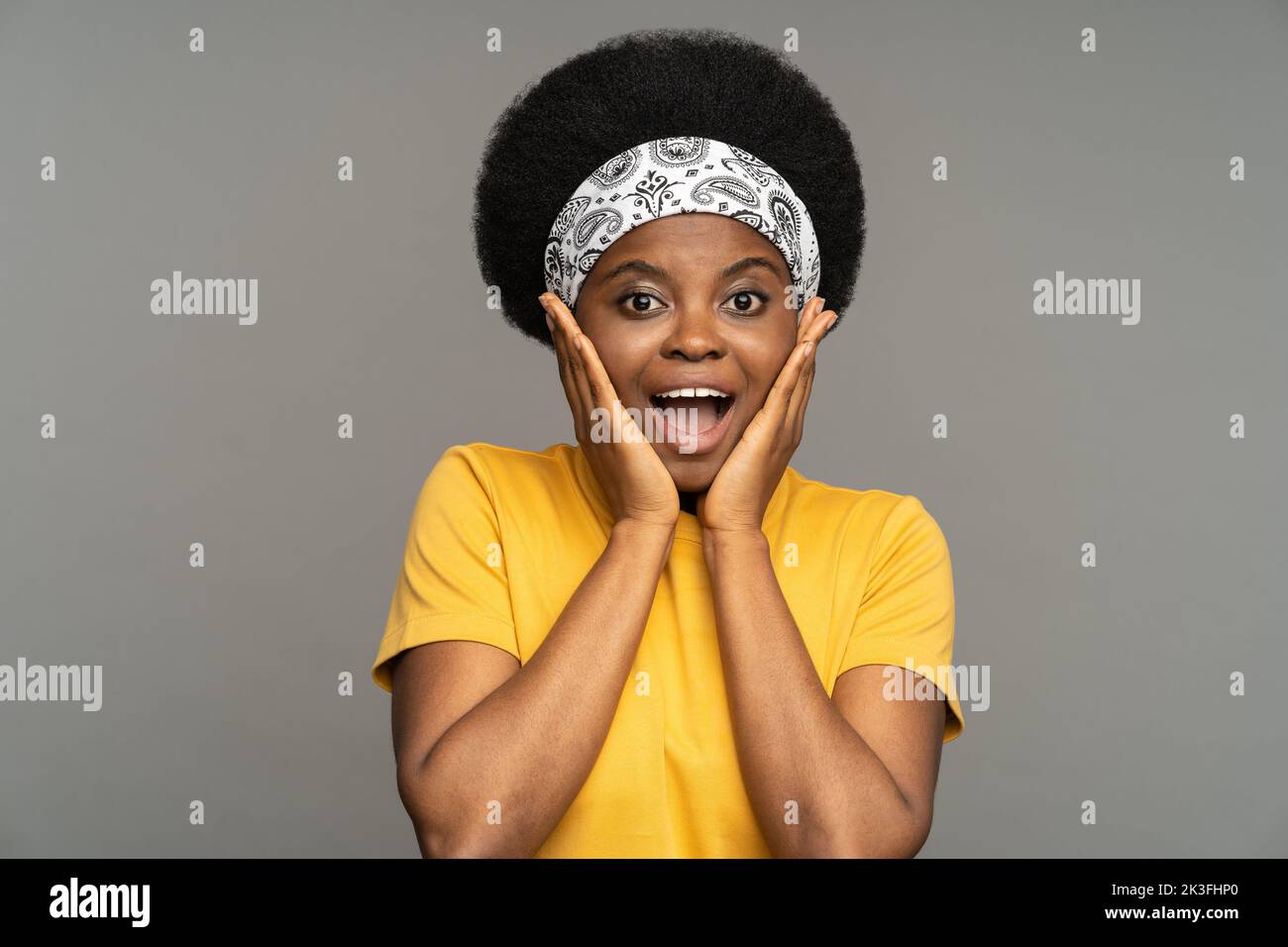 Afroamerikanische Frau führt Skizze mit amüsiert und verwirrt Ausdruck gegen Studiowand Stockfoto