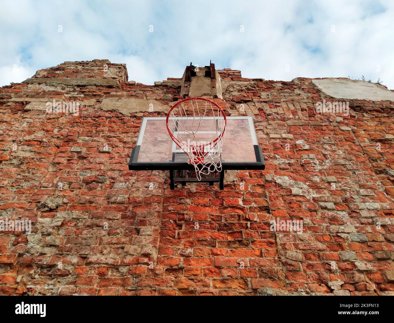 Altes und abgenutztes Outdoor-Basketballnetz auf dem Hintergrund der roten Backsteinmauer, urbaner Spielplatz, Innenstadt in der Stadt Stockfoto