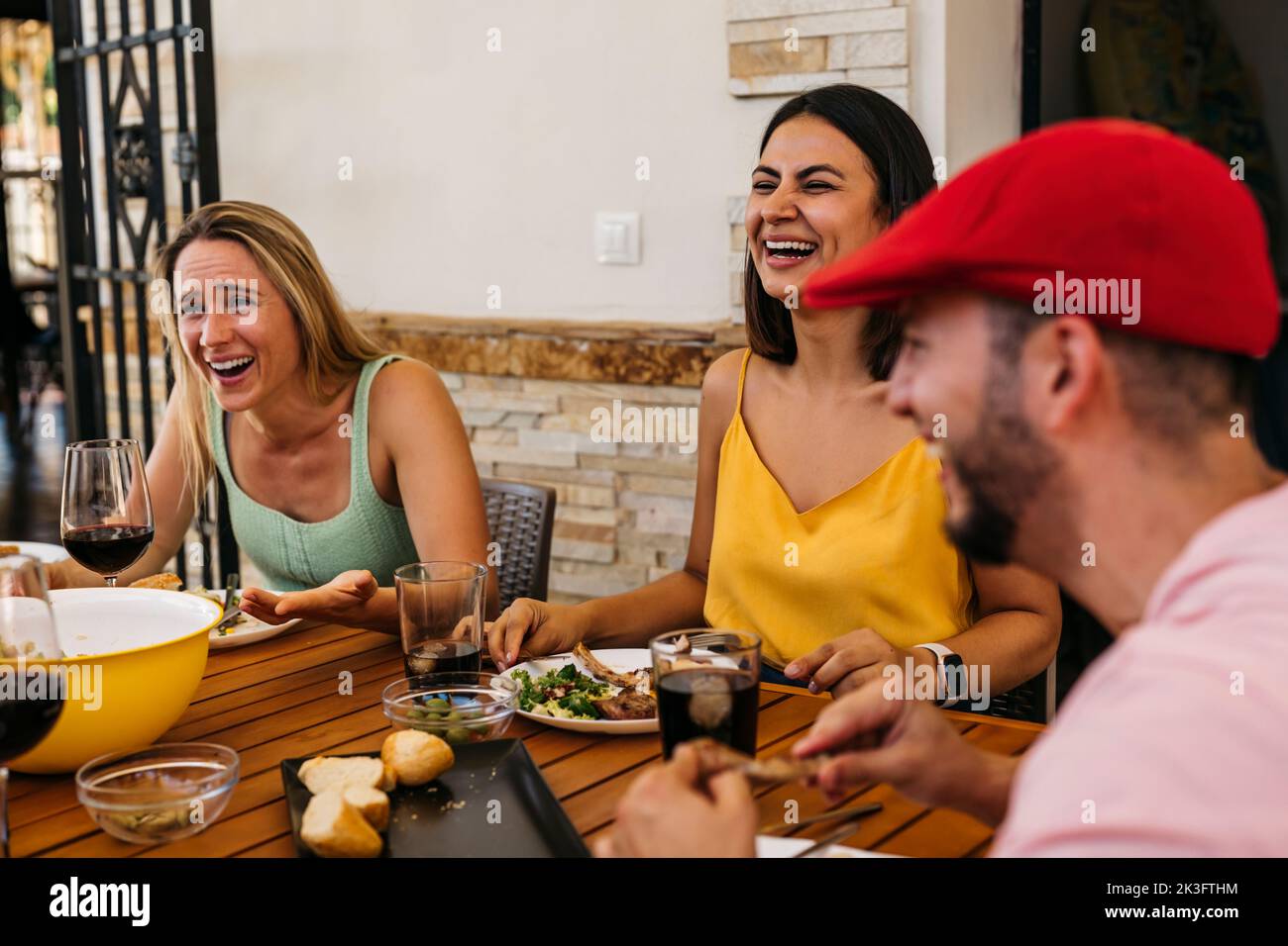 Ein brünette Mädchen und ein blondes Mädchen lachen, während sie mit einigen Freunden ein Essen feiern Stockfoto