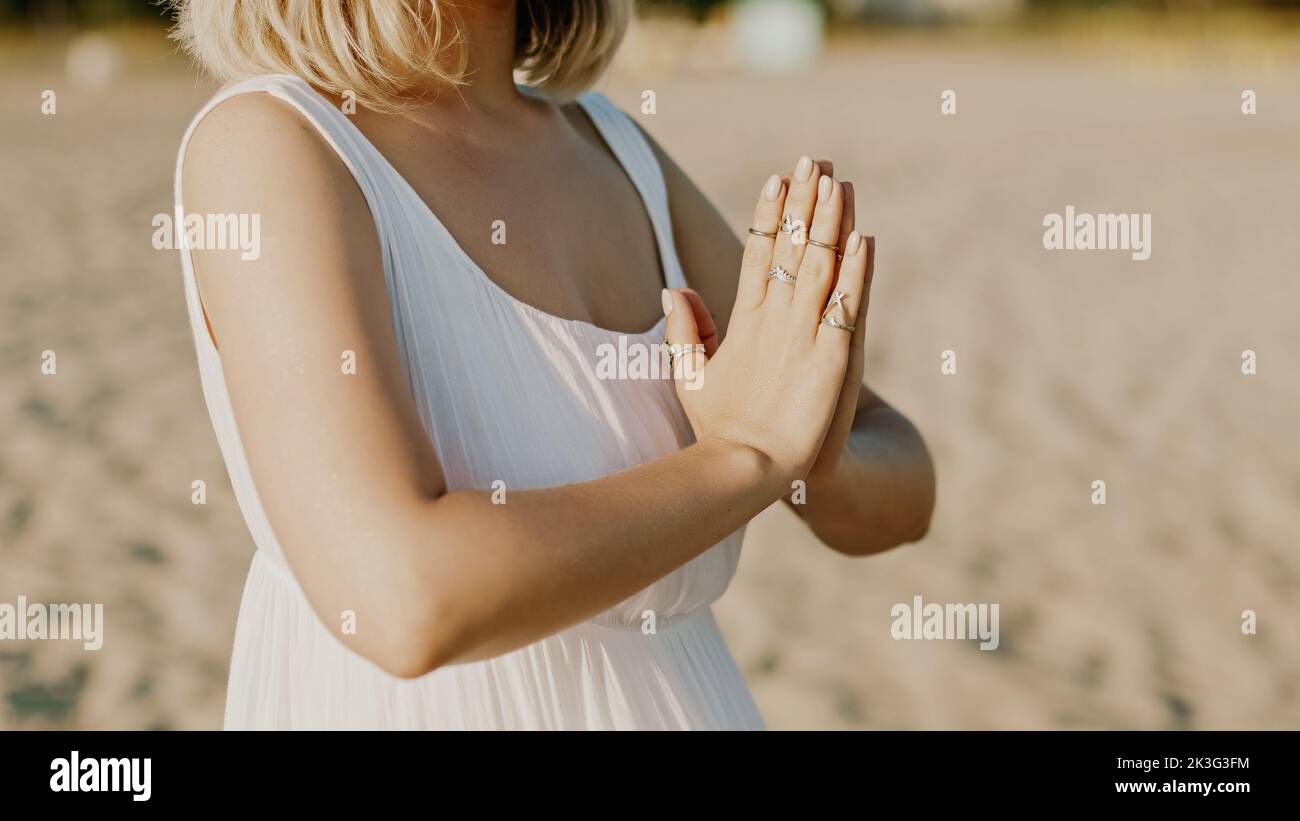 Die betende, meditierende Frau, die Mantras liest, richtet Gedanken, Bitten oder Dankbarkeit an das Universum. Strand, Morgen in der Nähe des Meeres. Spiritualität, Religion, Gott Stockfoto