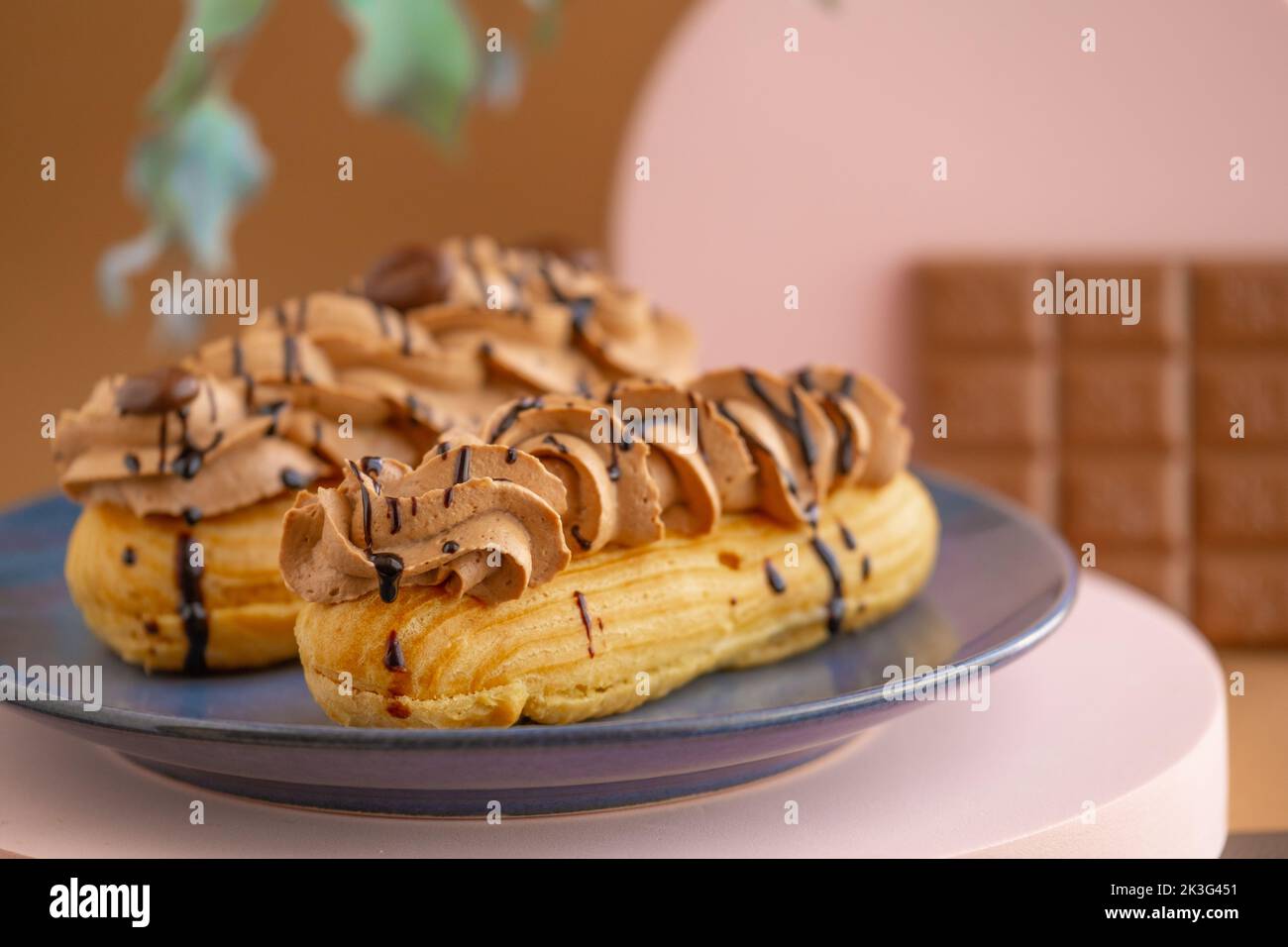 Eclairs Kuchen mit Schokoladencreme und Schokoriegel auf braunem Hintergrund.Süßigkeiten und Desserts. Backwaren und Desserts.Eclairs Kuchen. Stockfoto