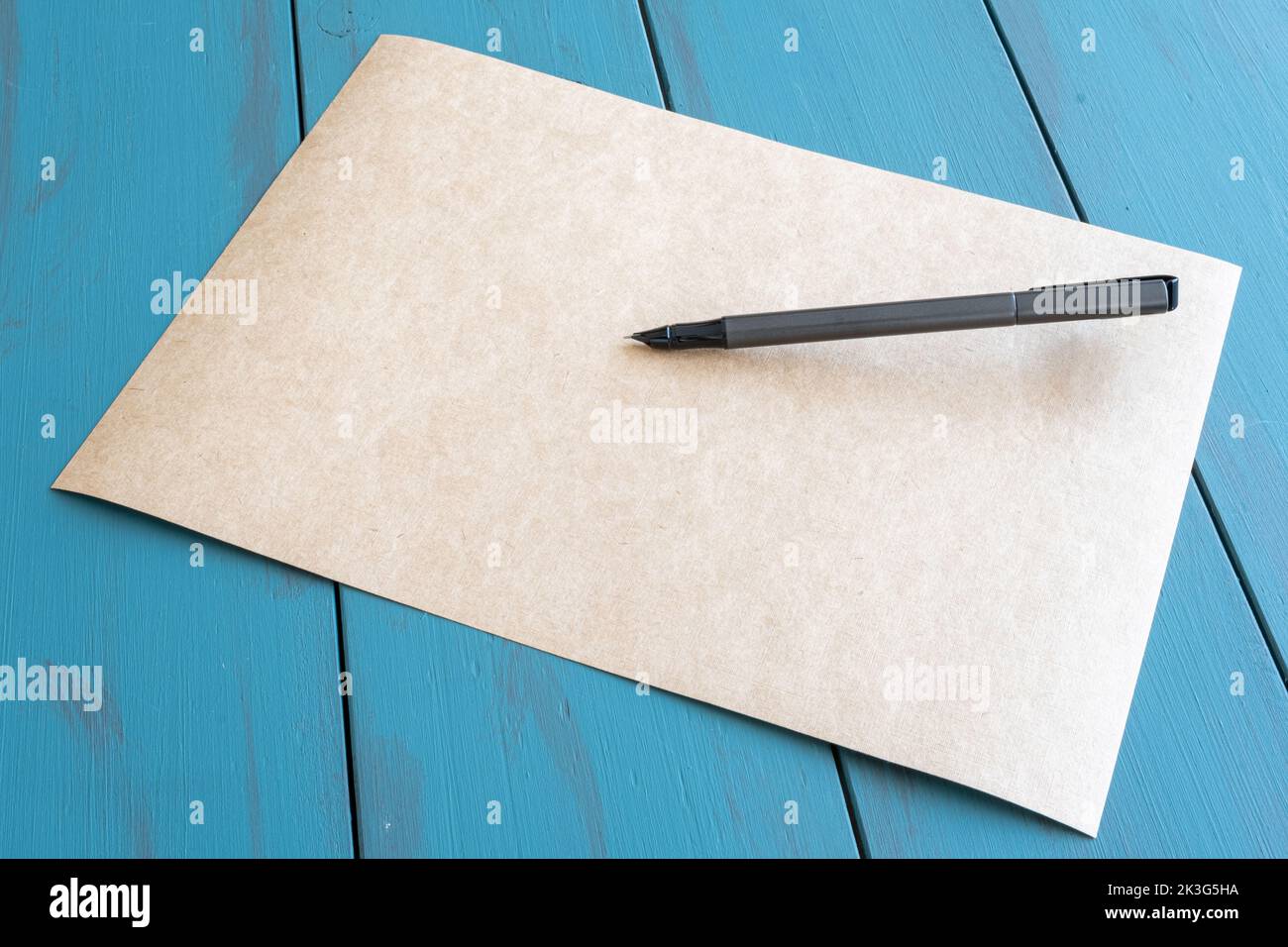 Grauer Füllfederhalter auf einer leeren braunen Papierseitenansicht. Stockfoto