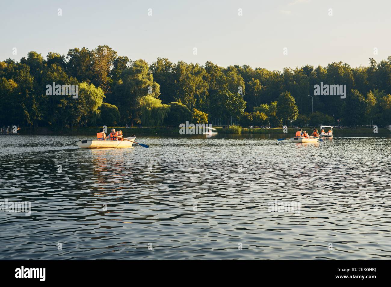 Die Menschen entspannen sich im Sommer im Park am Teich, Bootstouren und Katamarane. Vorderansicht. Stockfoto