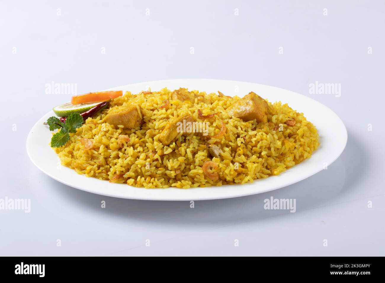 Motton dhum biriyani mit Jeera-Reis und Gewürzen in irdenen Geschirr mit Raitha und Zitroneneingelegter auf grauem Hintergrund angeordnet Stockfoto