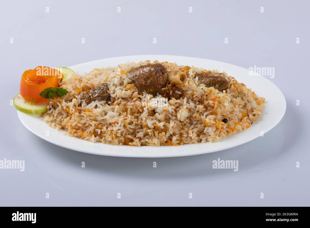 Motton dhum biriyani mit Jeera-Reis und Gewürzen in irdenen Geschirr mit Raitha und Zitroneneingelegter auf grauem Hintergrund angeordnet Stockfoto