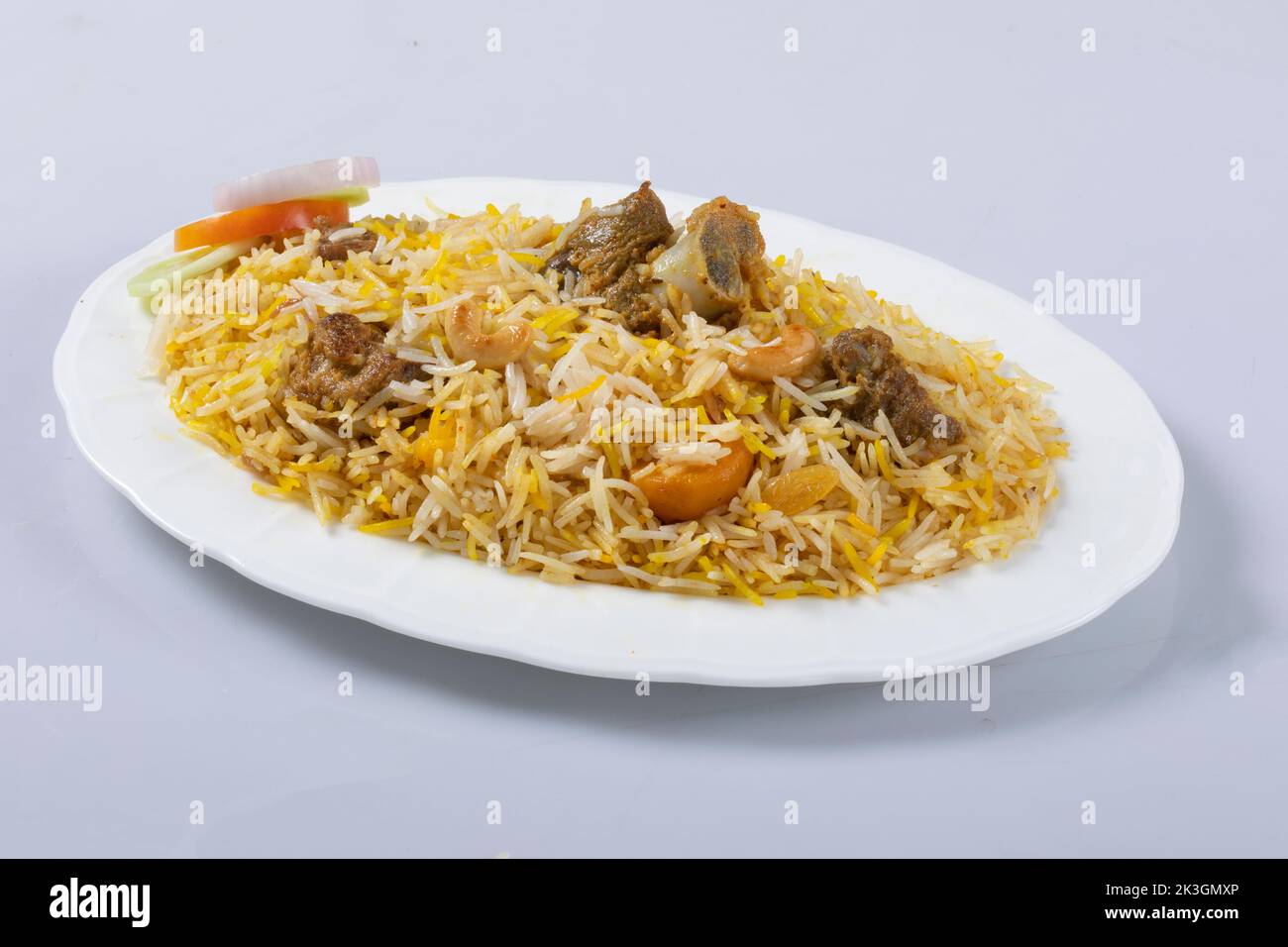 Motton dhum biriyani mit Jeera-Reis und Gewürzen in irdenen Geschirr mit Raitha und Zitroneneingelegter auf grauem Hintergrund angeordnet Stockfoto