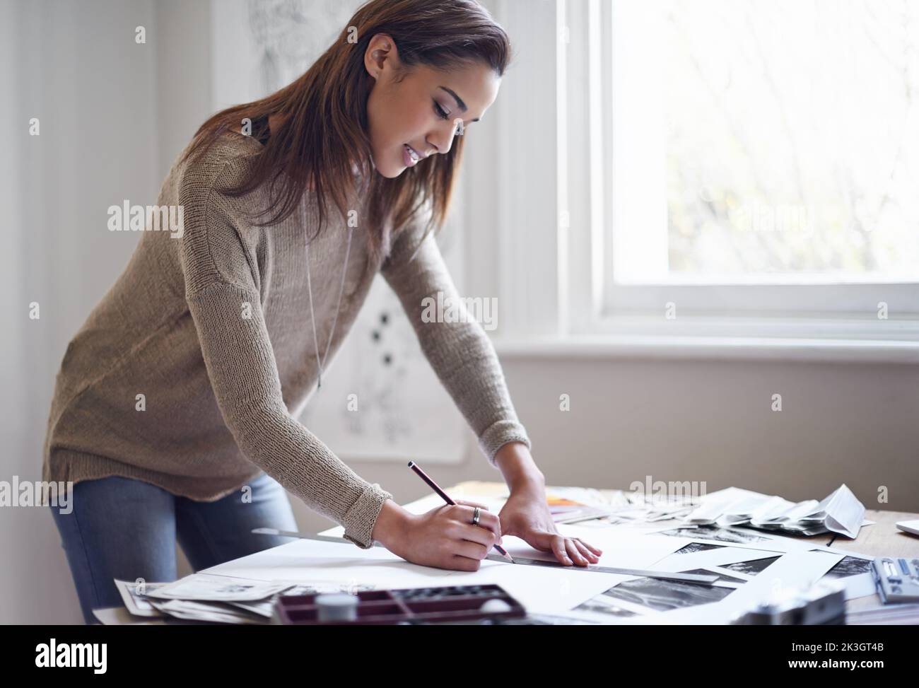 Sich kreativ auszudrücken. Eine junge Frau, die zu Hause an ihrem Portfolio arbeitet. Stockfoto