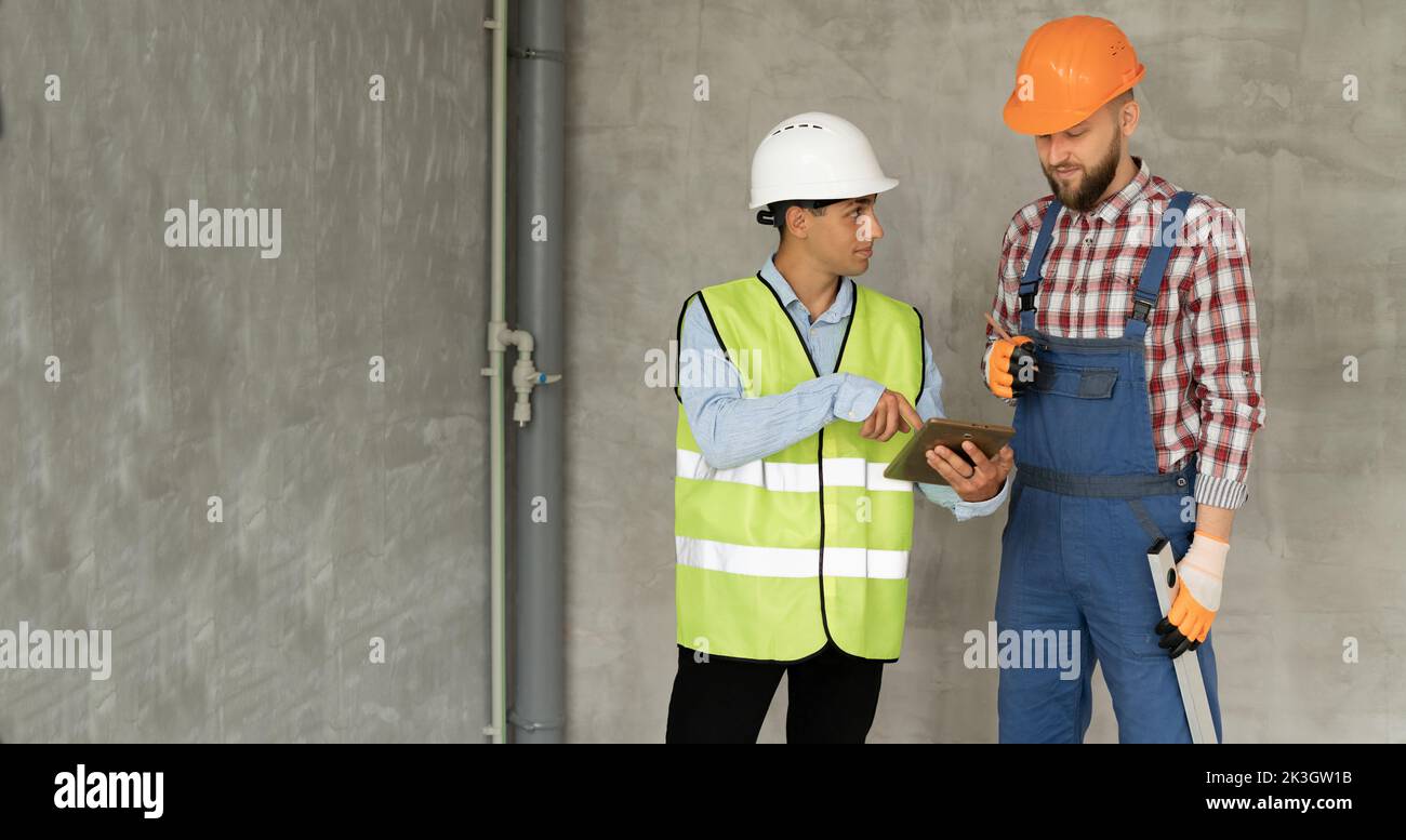 Muslimischer Baumeister und Bauingenieur mit Tablet-pc-Computer in Innenräumen. Treffen einer Entscheidung über die Durchführung von Reparaturarbeiten. Gebäude, Renovierung, Technolo Stockfoto