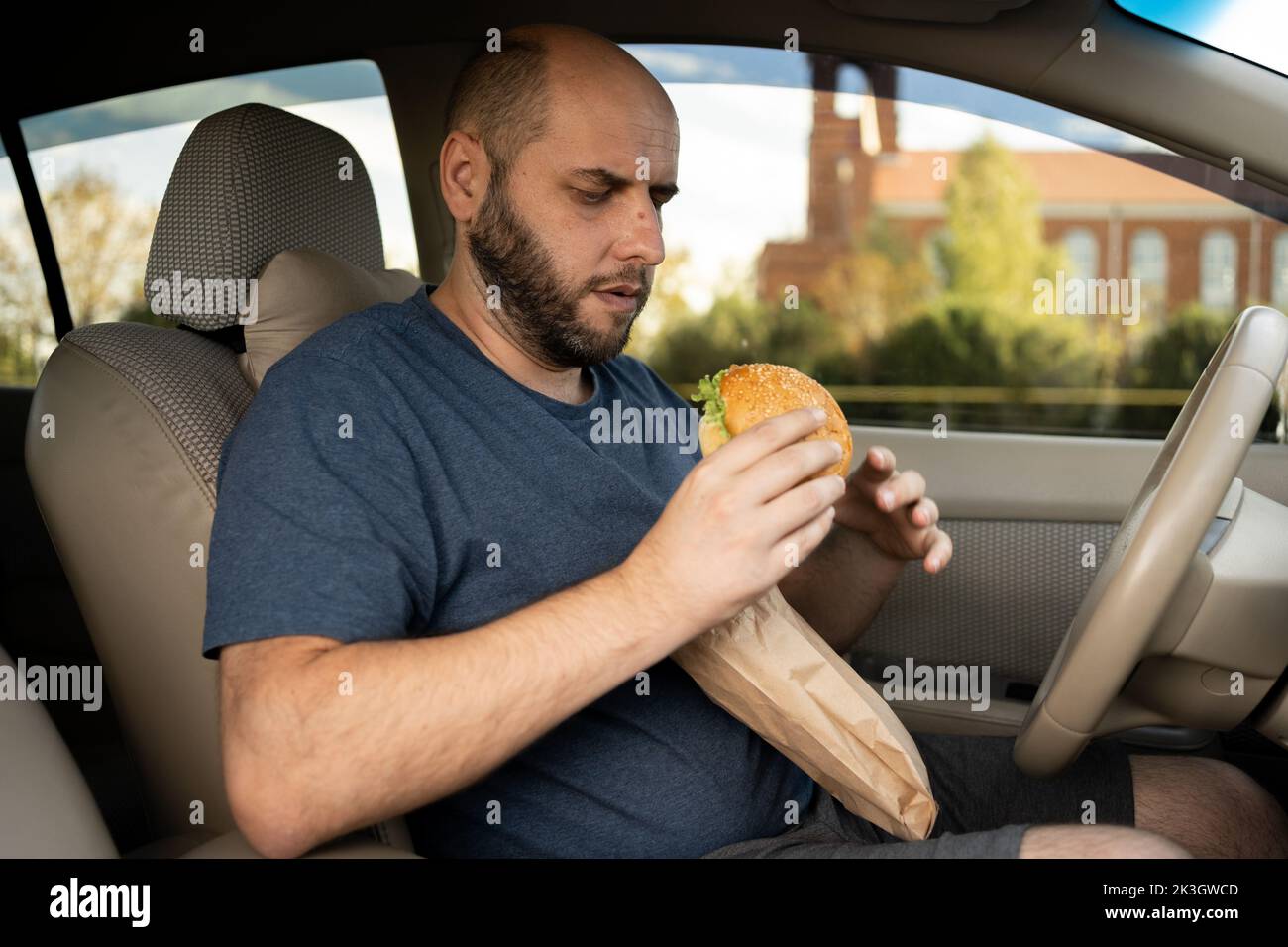 Taxifahrer essen Burger im Auto, da der Verkehr am Morgen sehr schlecht ist. Essen Sie Hamburger im Auto Stockfoto