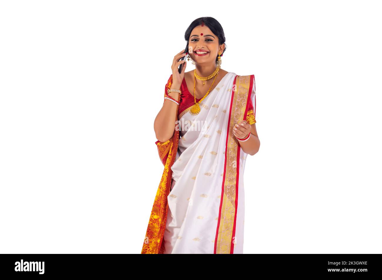 Junge bengalische Frau, die auf dem Mobiltelefon vor weißem Hintergrund spricht Stockfoto