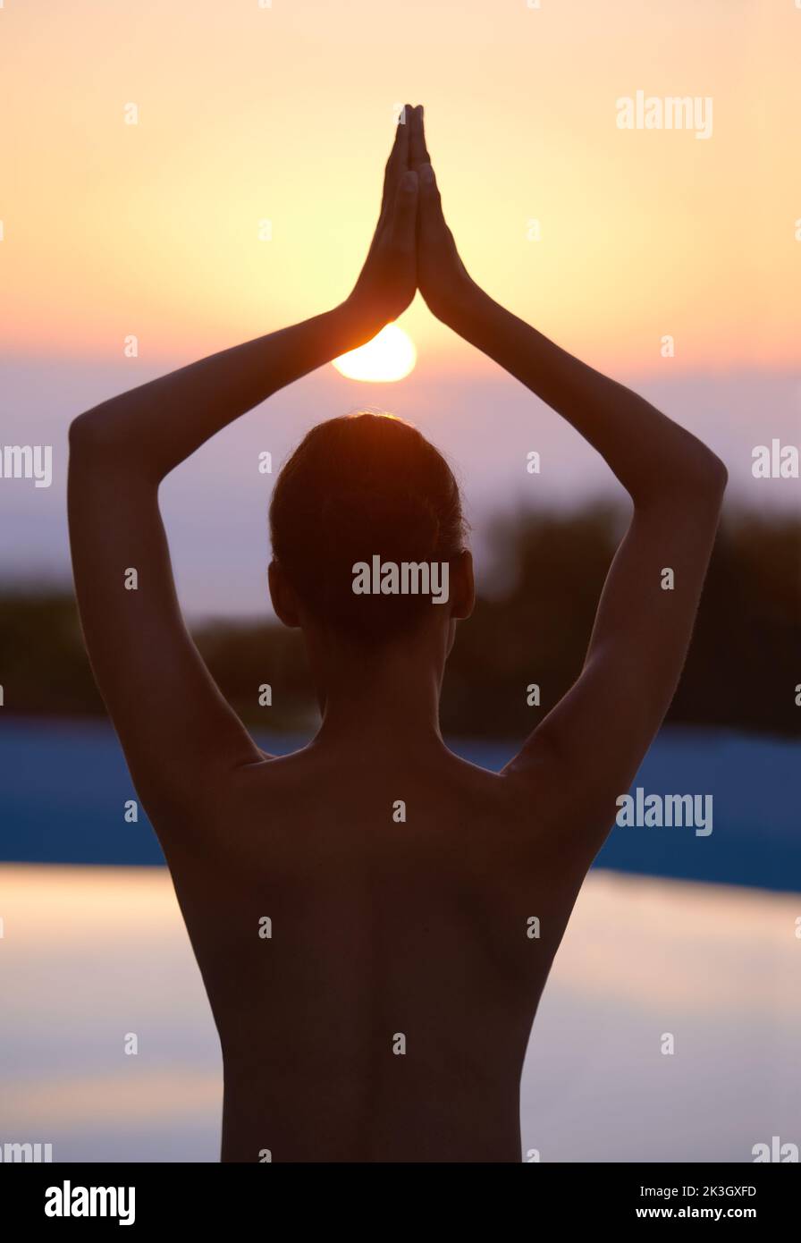 Ruhe in der Natur finden. Eine schöne junge Frau in einer Yoga-Pose bei Sonnenuntergang. Stockfoto