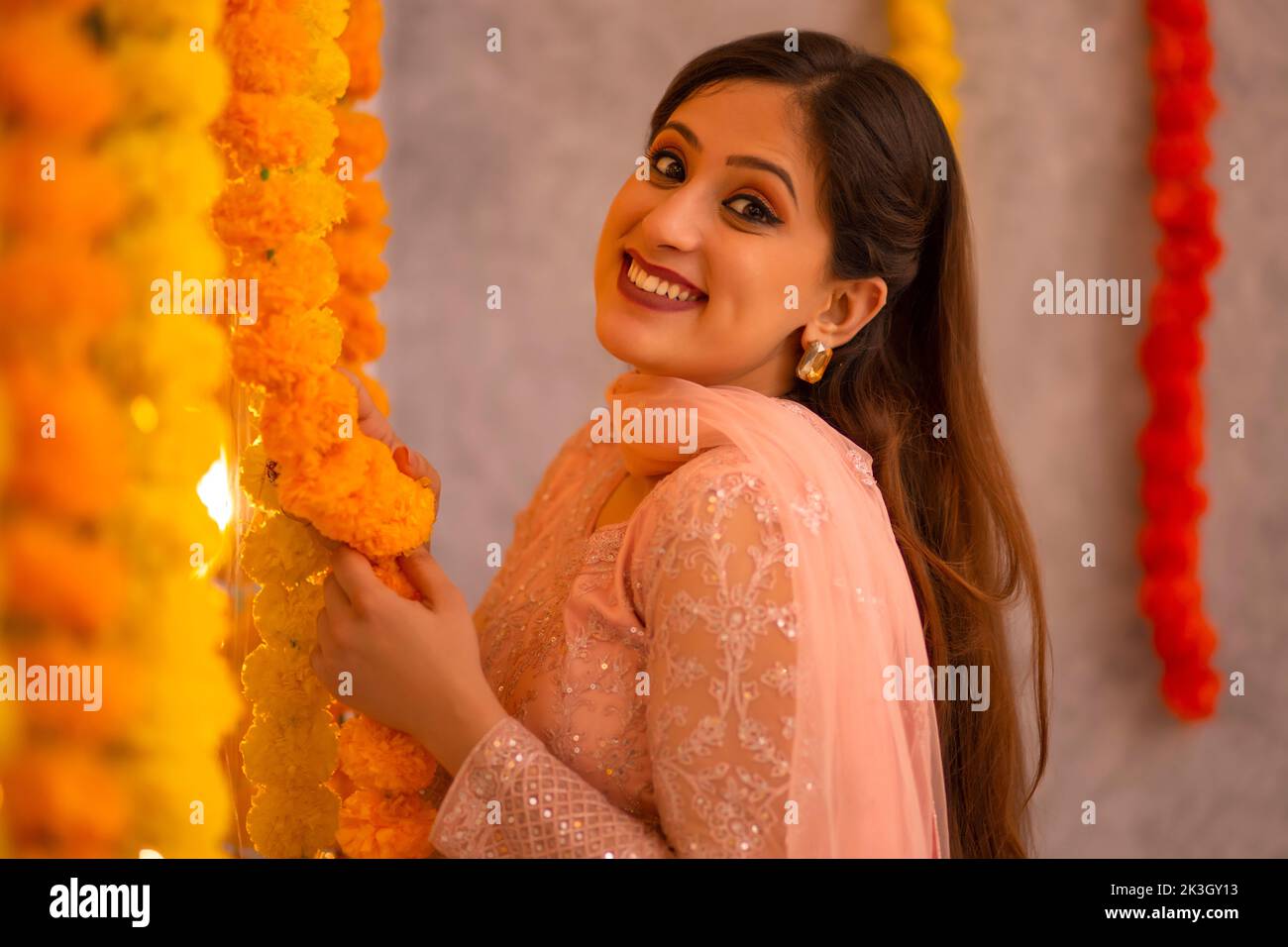 Frau, die das Büro mit Blumengirlande anlässlich der Diwali schmückt Stockfoto