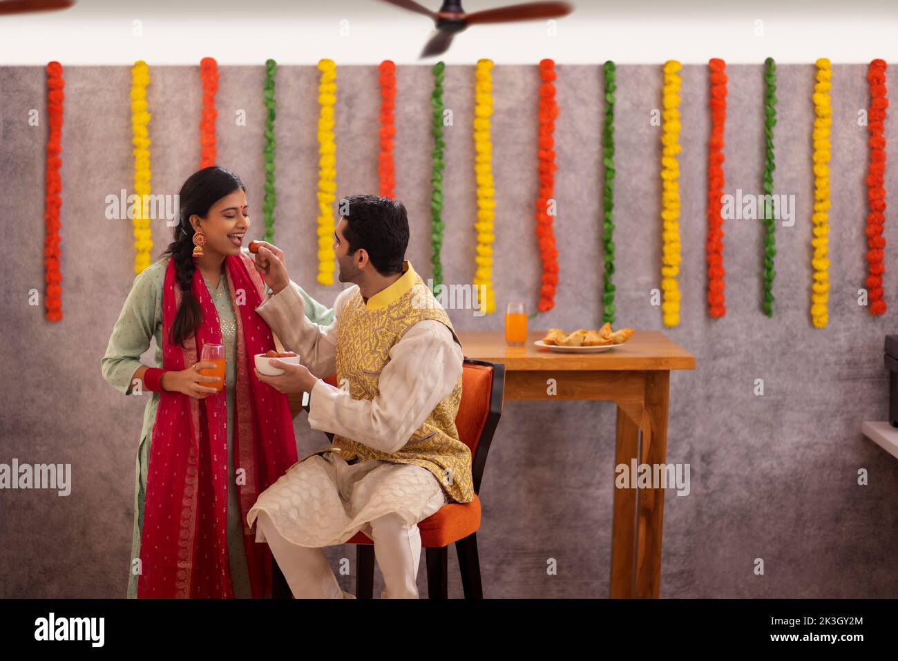 Mitarbeiter, der während der Diwali-Feier seinem Kollegen Gulab-Jamun zufütterte Stockfoto