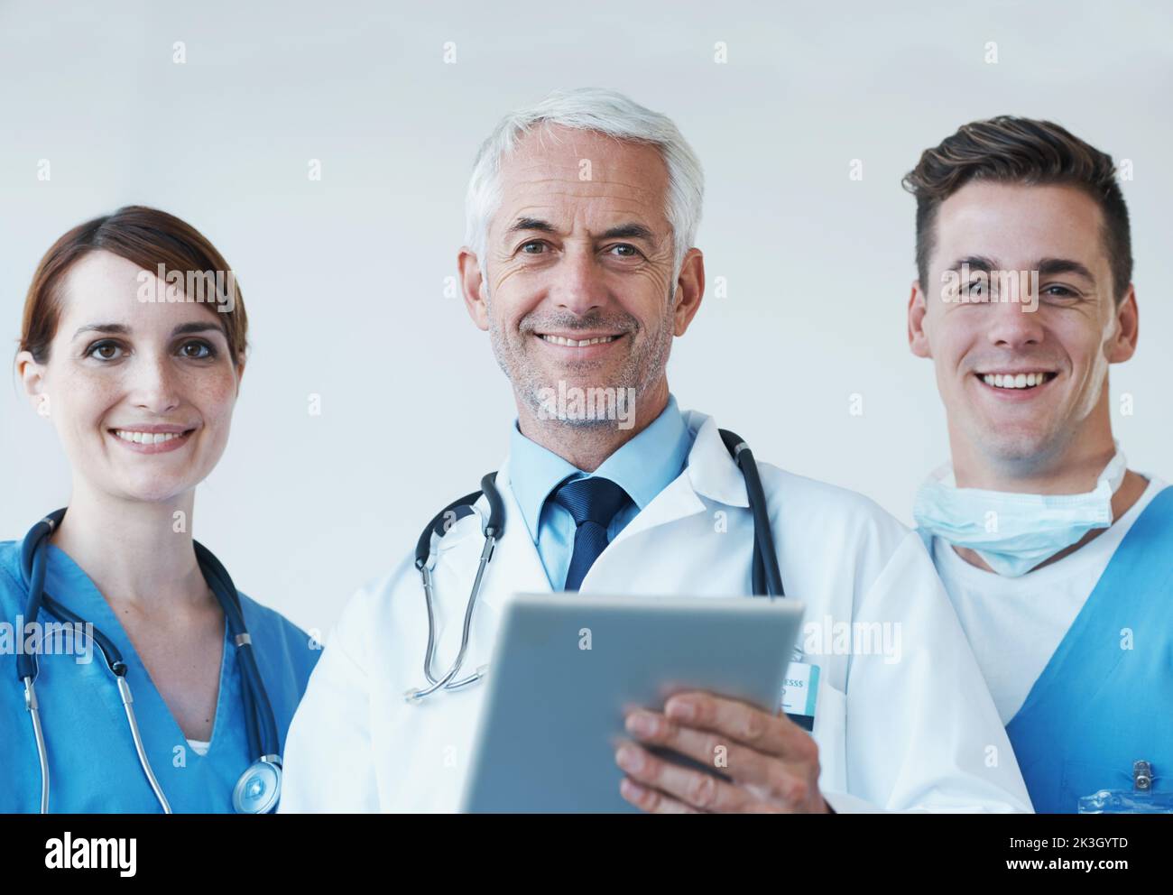 Die Technologie ebnet den Weg für neue medizinische Entdeckungen. Drei Mediziner diskutieren über Informationen, die auf einem digitalen Tablet präsentiert werden. Stockfoto