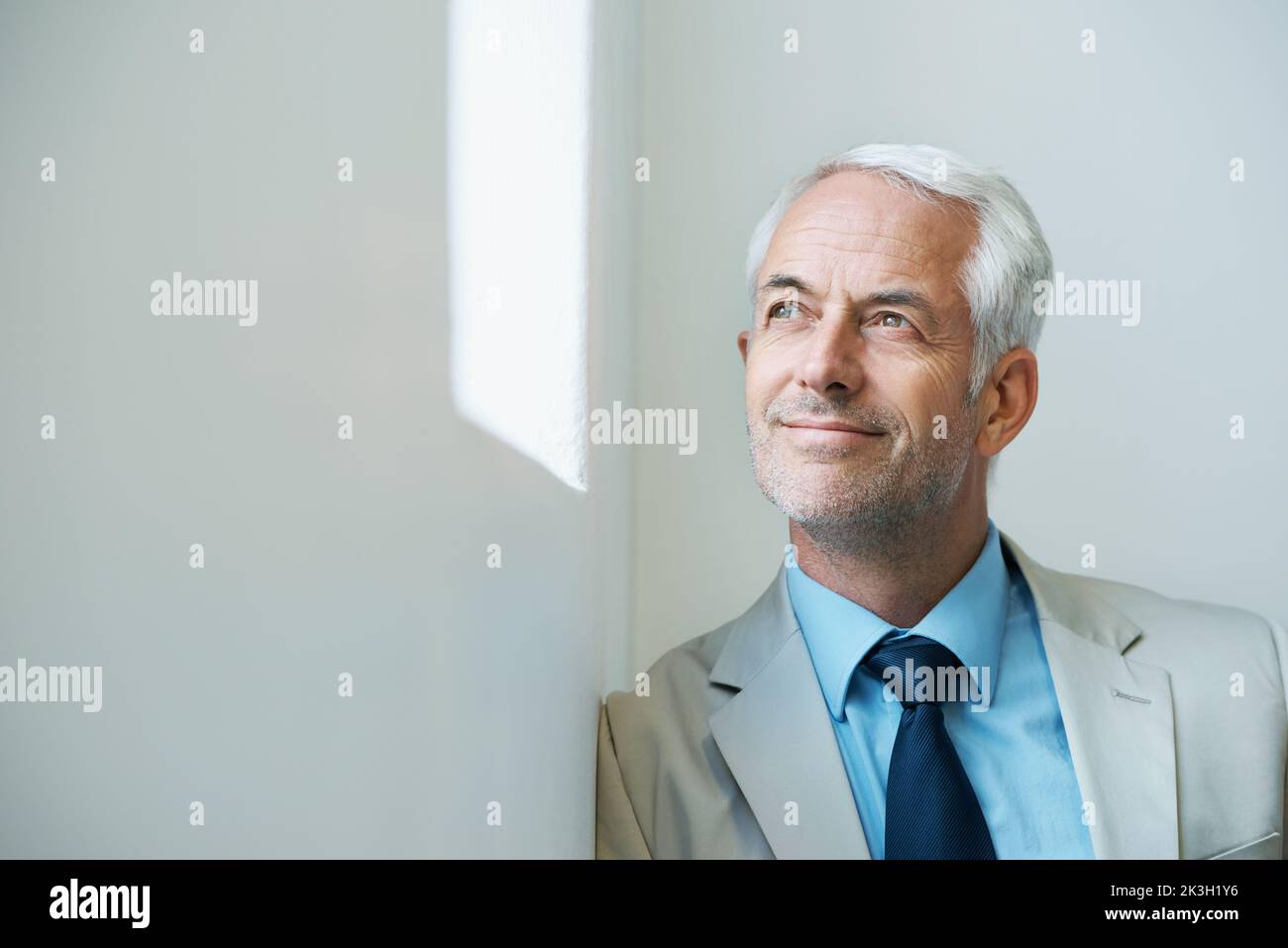 Blick in die Zukunft. Ein nachdenklich aussehender reifer Geschäftsmann, der aus einem Fenster schaut. Stockfoto