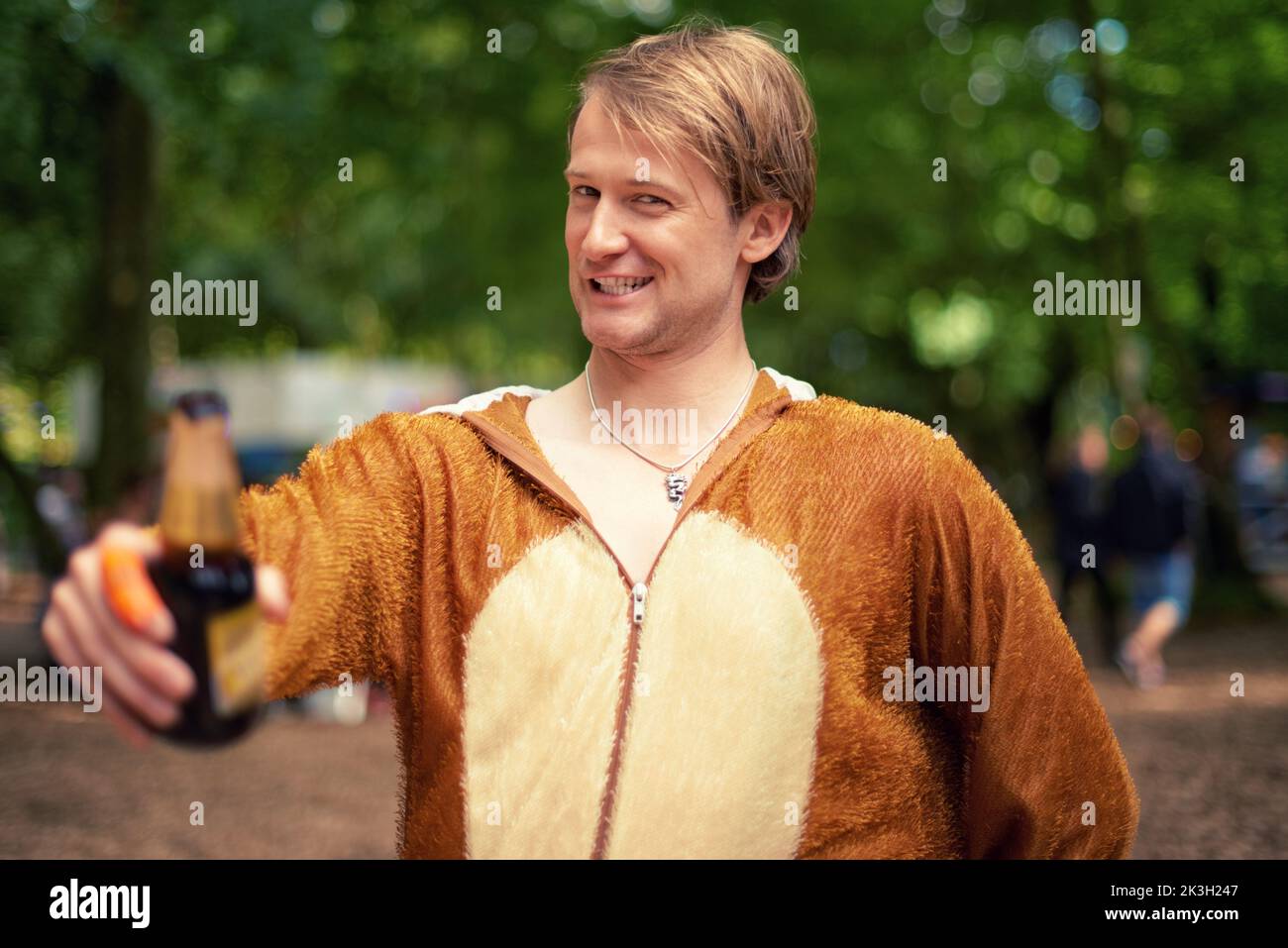 Partytier. Porträt eines jungen Mannes, der draußen ein Bier trinkt, während er in einem Bärenanzug gekleidet ist. Stockfoto