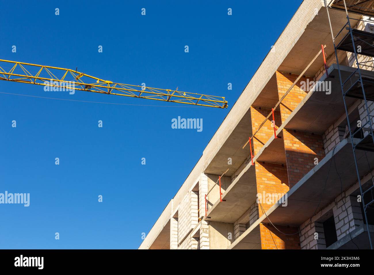 Isolierung der Außenwände eines Gebäudes im Bau. Die Wände des im Bau befindlichen Gebäudes sind von Gerüsten für Arbeiten umgeben Stockfoto