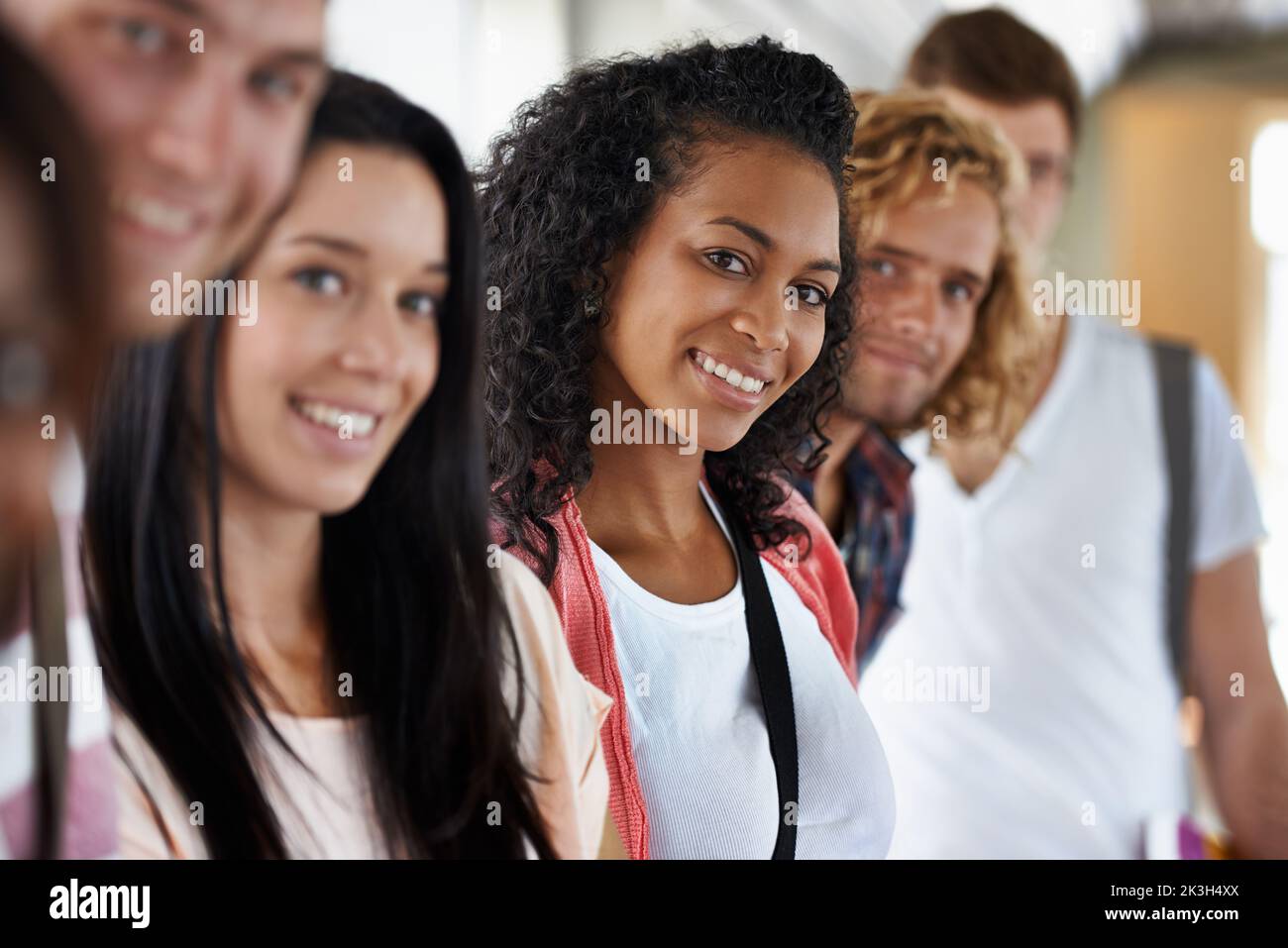 Sie liebt das Universitätsleben. Porträt einer schönen jungen College-Studentin, die mit ihren Freunden steht. Stockfoto