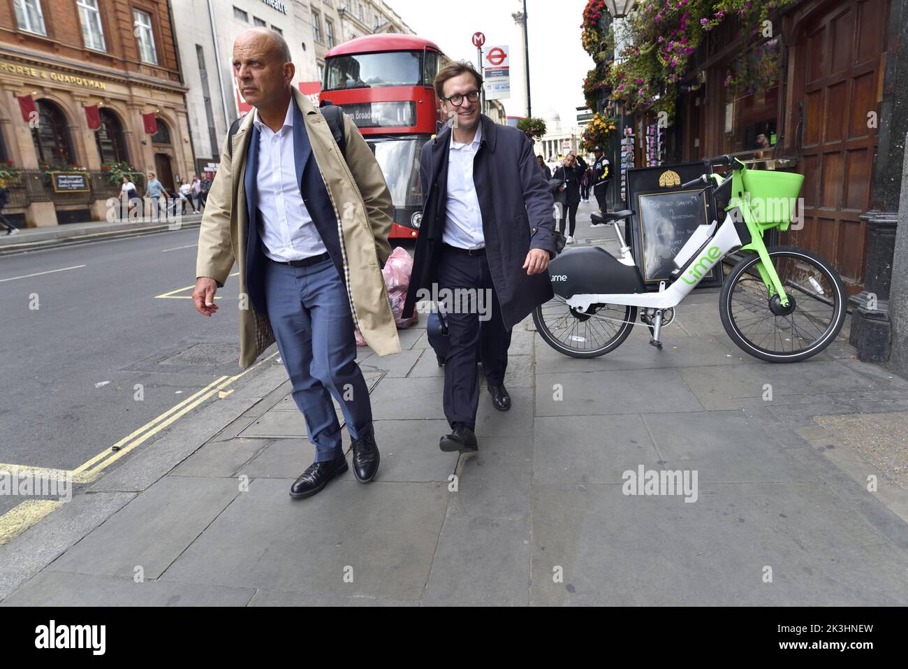 London, England, Großbritannien. Zwei Männer gehen Whitehall entlang. London Bus und Lime Leihrad Stockfoto