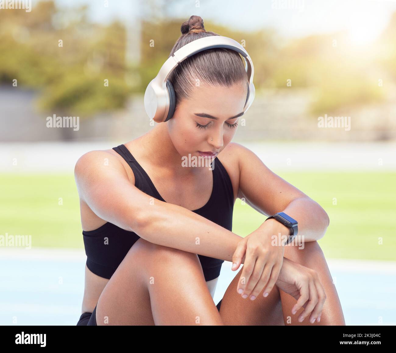 Sportläuferin Frau hört Musik in der Pause von Training, Bewegung und Fitness-Workout. Müde Sportler ruhen sich aus, um sich von Schmerzen zu erholen, beugen Muskeln vor Stockfoto