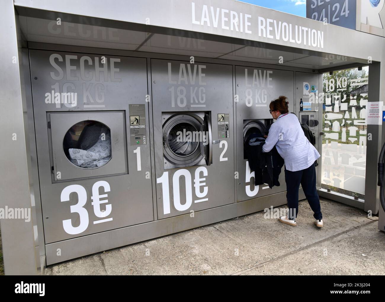 Frau, die in Frankreich einen externen Waschautomaten namens Laverie Revolution benutzt Stockfoto