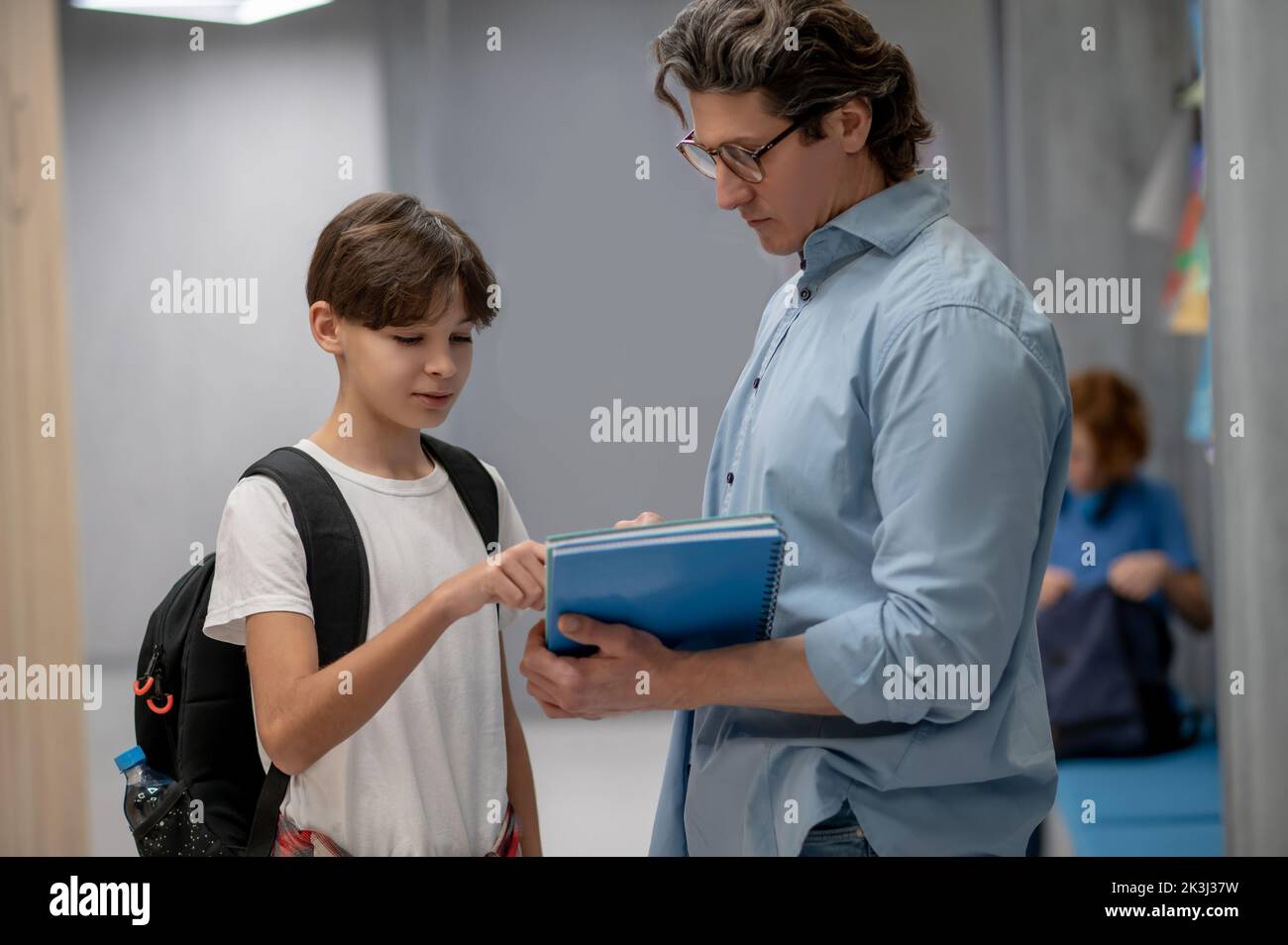 Der Schuljunge stellte Fragen an seinen Lehrer im Korridor Stockfoto