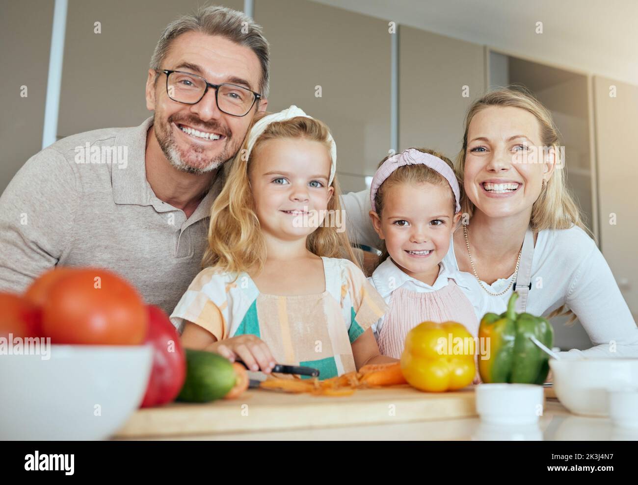 Familie, Gesundheit und Kinder mit Gemüse Ernährung für eine gesunde Ernährung, Mineralien oder Vitamine auf dem Küchentisch zu Hause. Portrait von glücklichen Eltern und Mädchen Stockfoto
