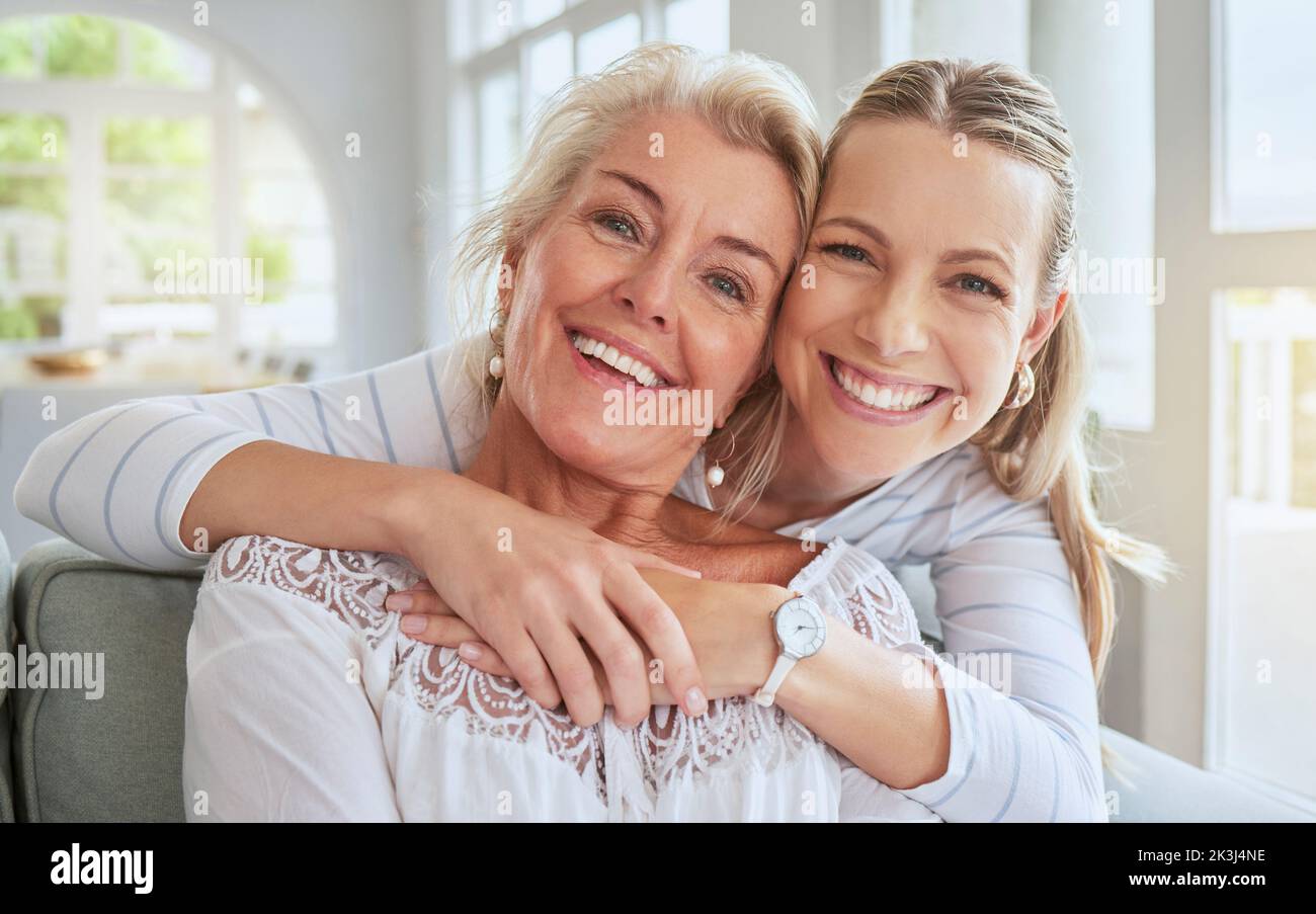 Frauen, Umarmung und Familienbindung am Muttertag in einem Wohnzimmer und häuslicher Einrichtung. Menschen porträtieren, lächeln und glückliche Frau mit Senioren und Ruhestand Stockfoto