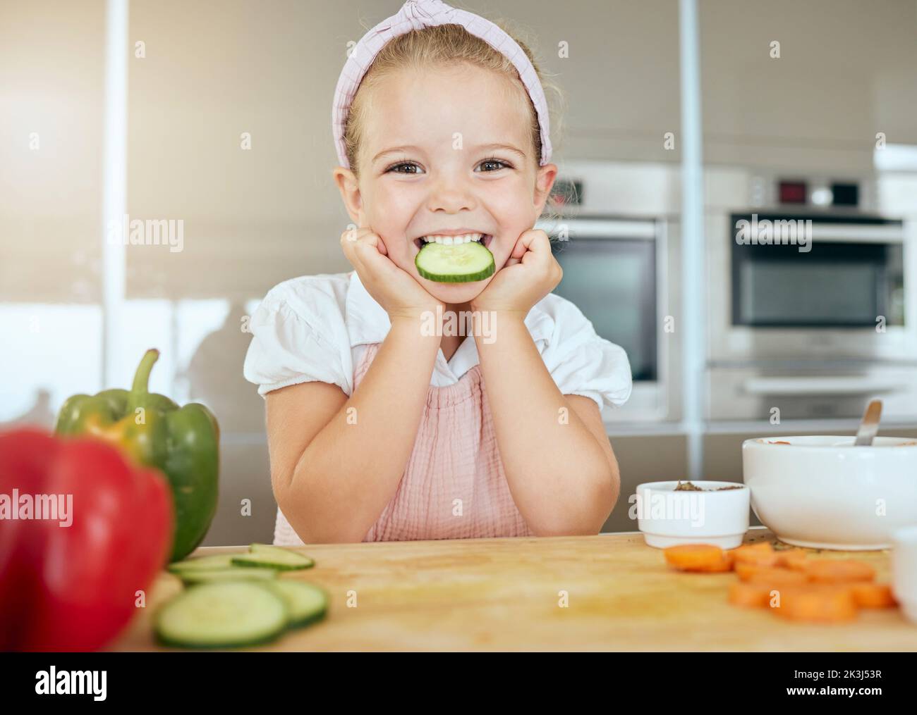 Nettes Mädchen mit einem Lächeln essen Gurke, kocht gesunde grüne Salat für eine Mahlzeit und lernen über die Ernährung Vorteile. Frisches Obst, Bio-Gemüse Stockfoto