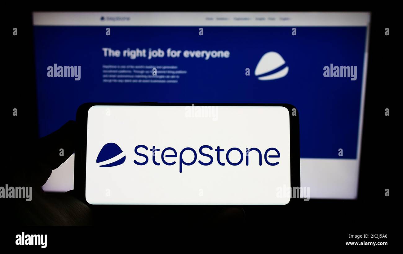 Person, die Smartphone mit Logo der deutschen Jobboard-Firma StepStone GmbH auf dem Bildschirm vor der Website hält. Konzentrieren Sie sich auf die Telefonanzeige. Stockfoto