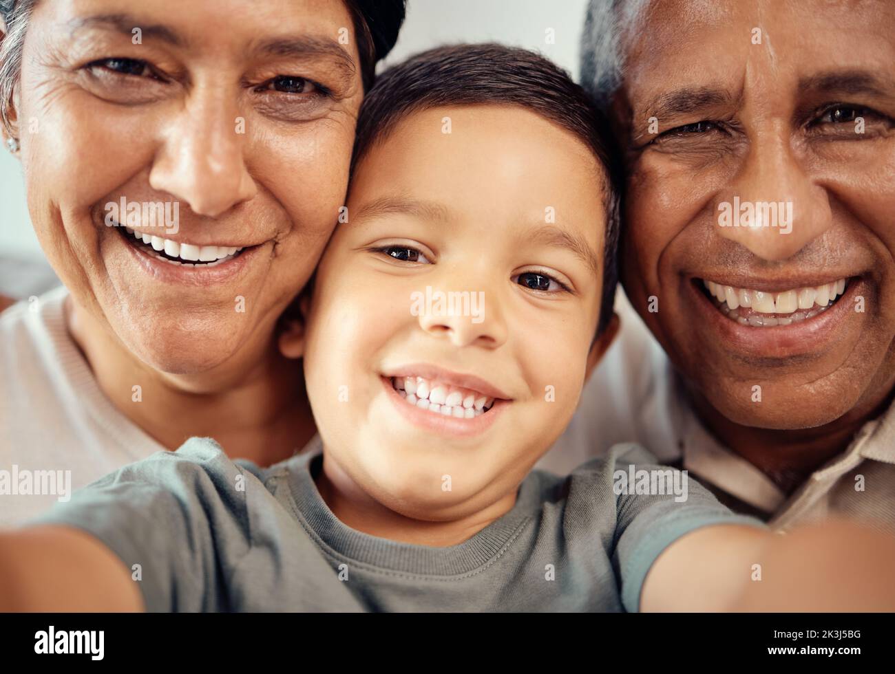 Junge machen Selfie mit glücklichen Großeltern, zusammen in Nahaufnahme oder Zoom-Porträt im Haus. Latino männliches Kind lächelt mit Oma und Opa im Makro mit Stockfoto